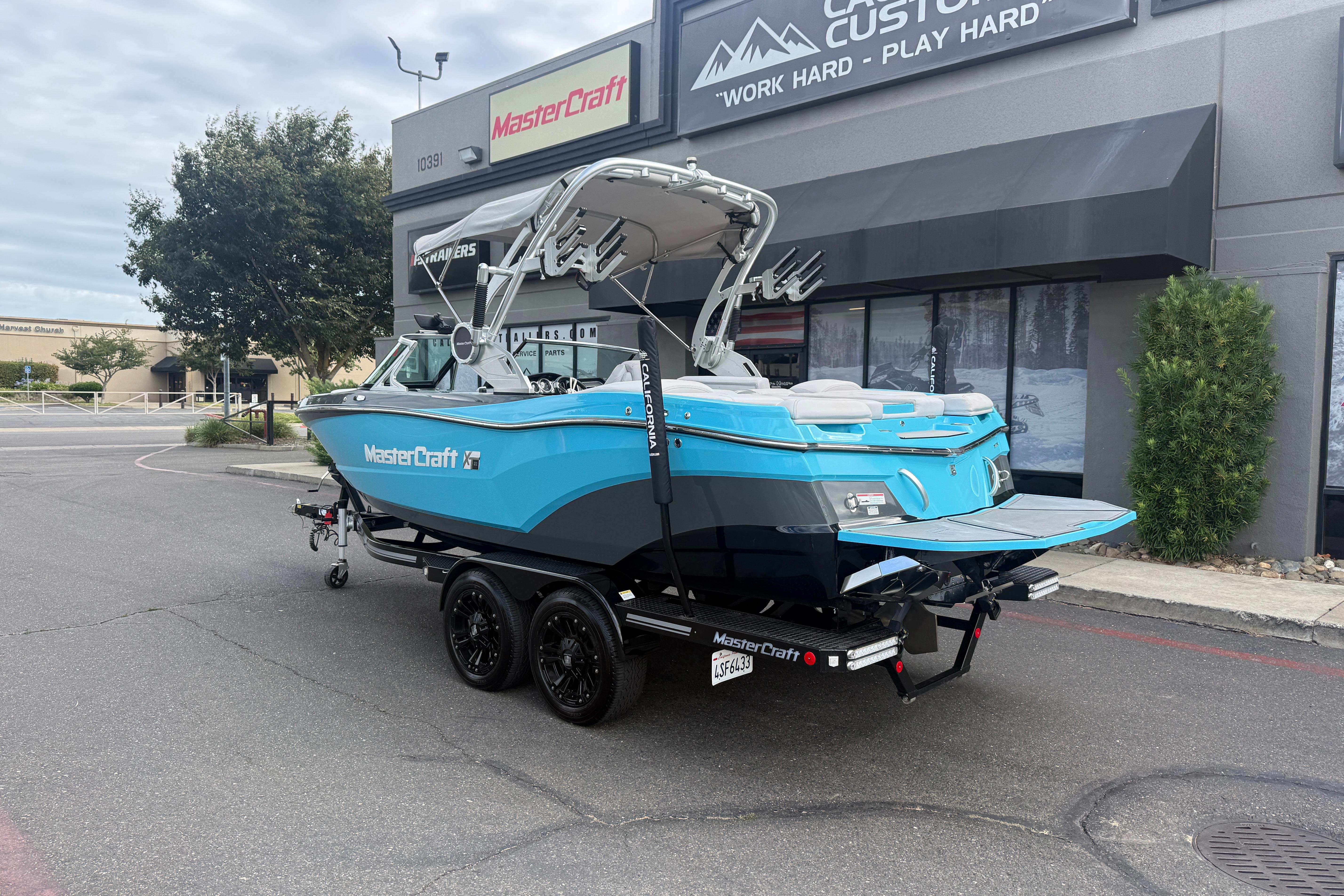 2018 MasterCraft XT21 boat in blue, parked outside a dealership.
