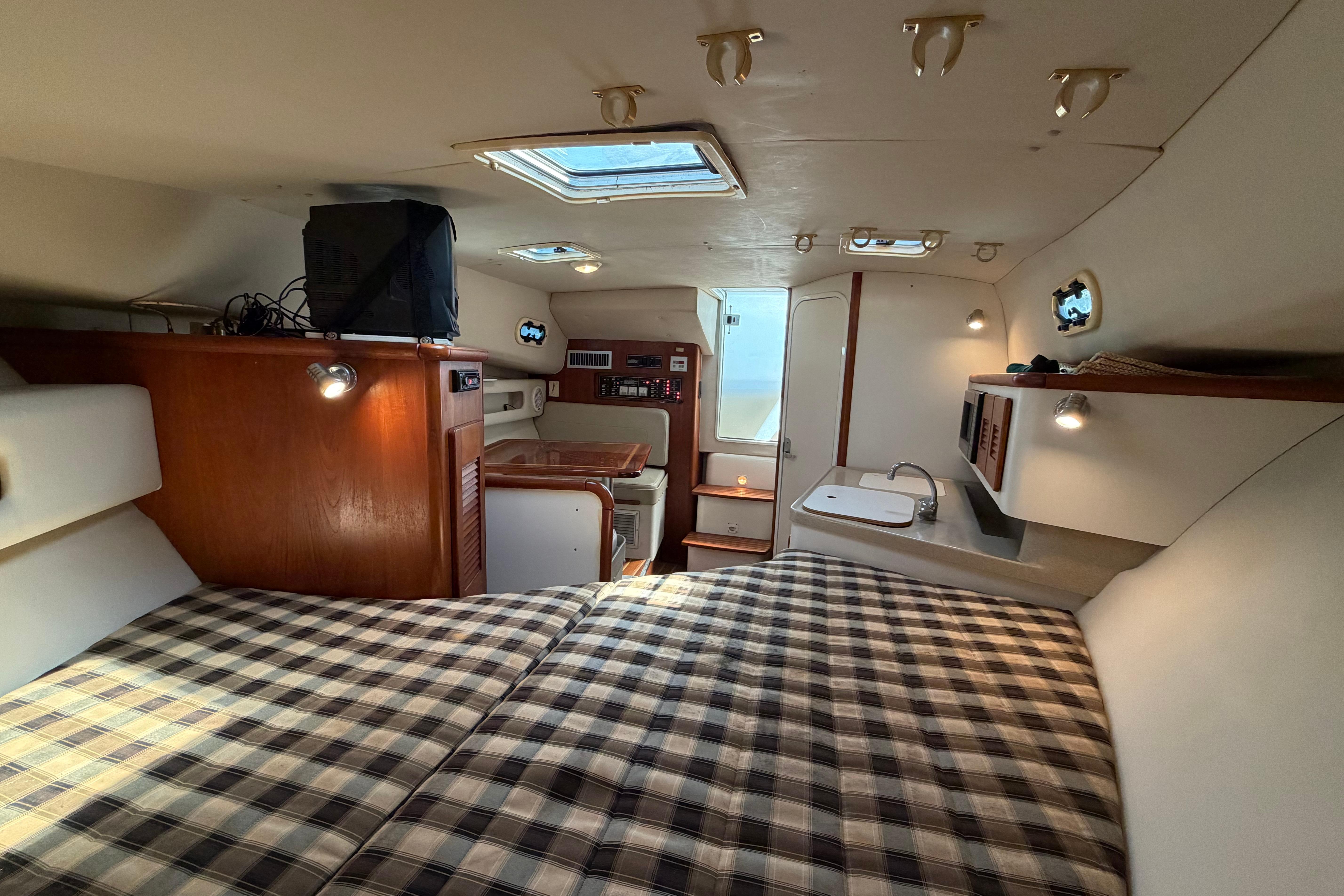 Interior of 2001 Pursuit 3000 Express boat with cozy cabin and plaid bedding.