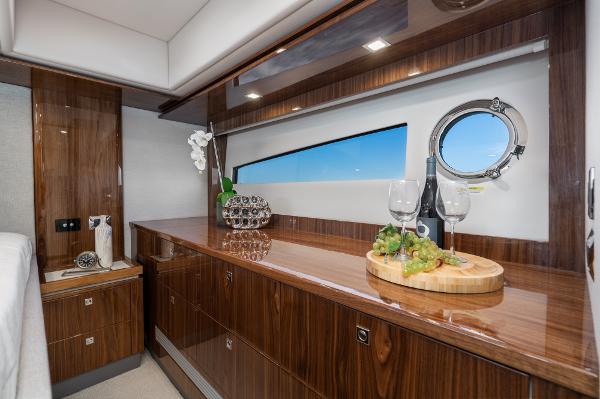 Luxurious interior of 2021 Riviera 5400 Sport Yacht with wooden cabinetry and ocean view.