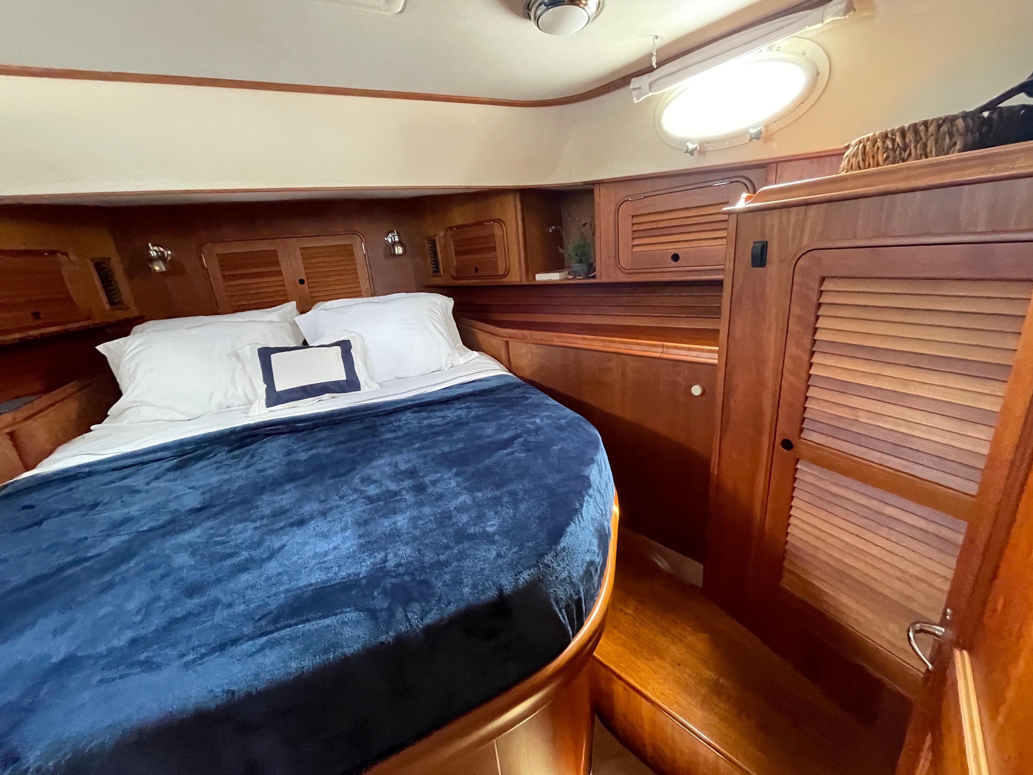 Luxurious cabin interior of 2007 Hinckley Talaria 44 Flybridge with wood finish and cozy bedding.
