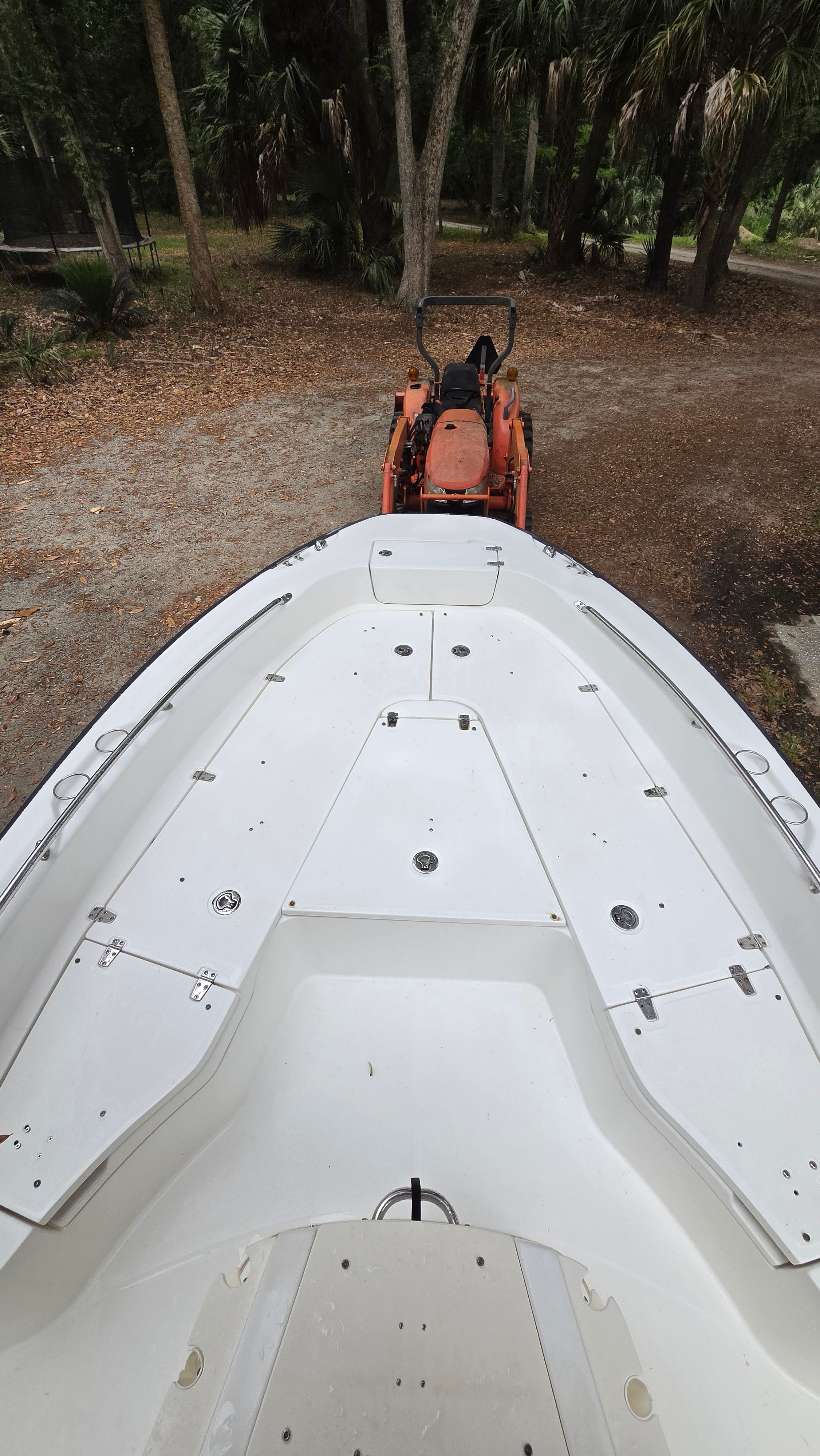 A 2008 Boston Whaler 230 Dauntless on a trailer, surrounded by trees.