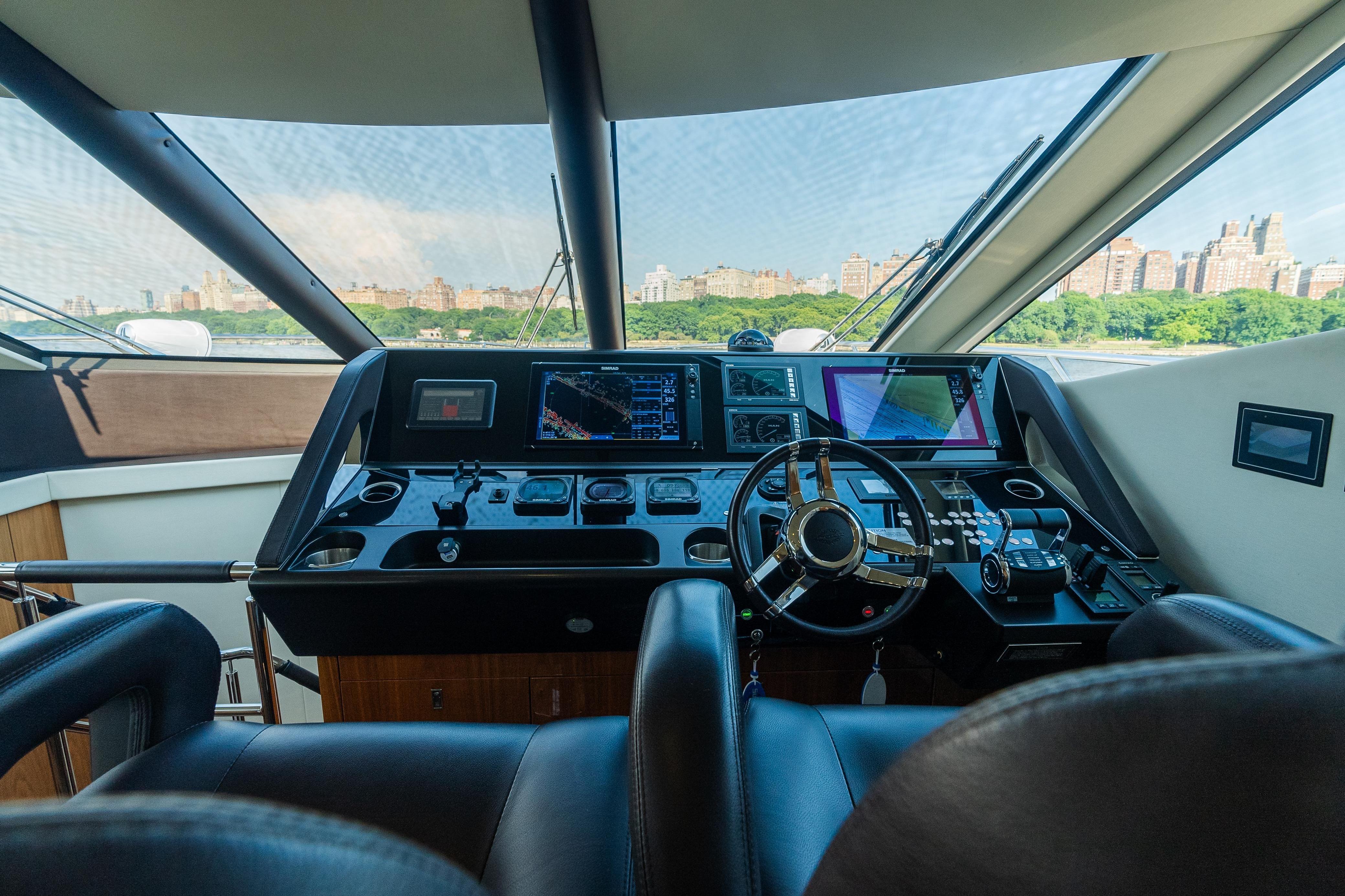 Luxurious helm of 2016 Sunseeker Manhattan 65 yacht with cityscape view.