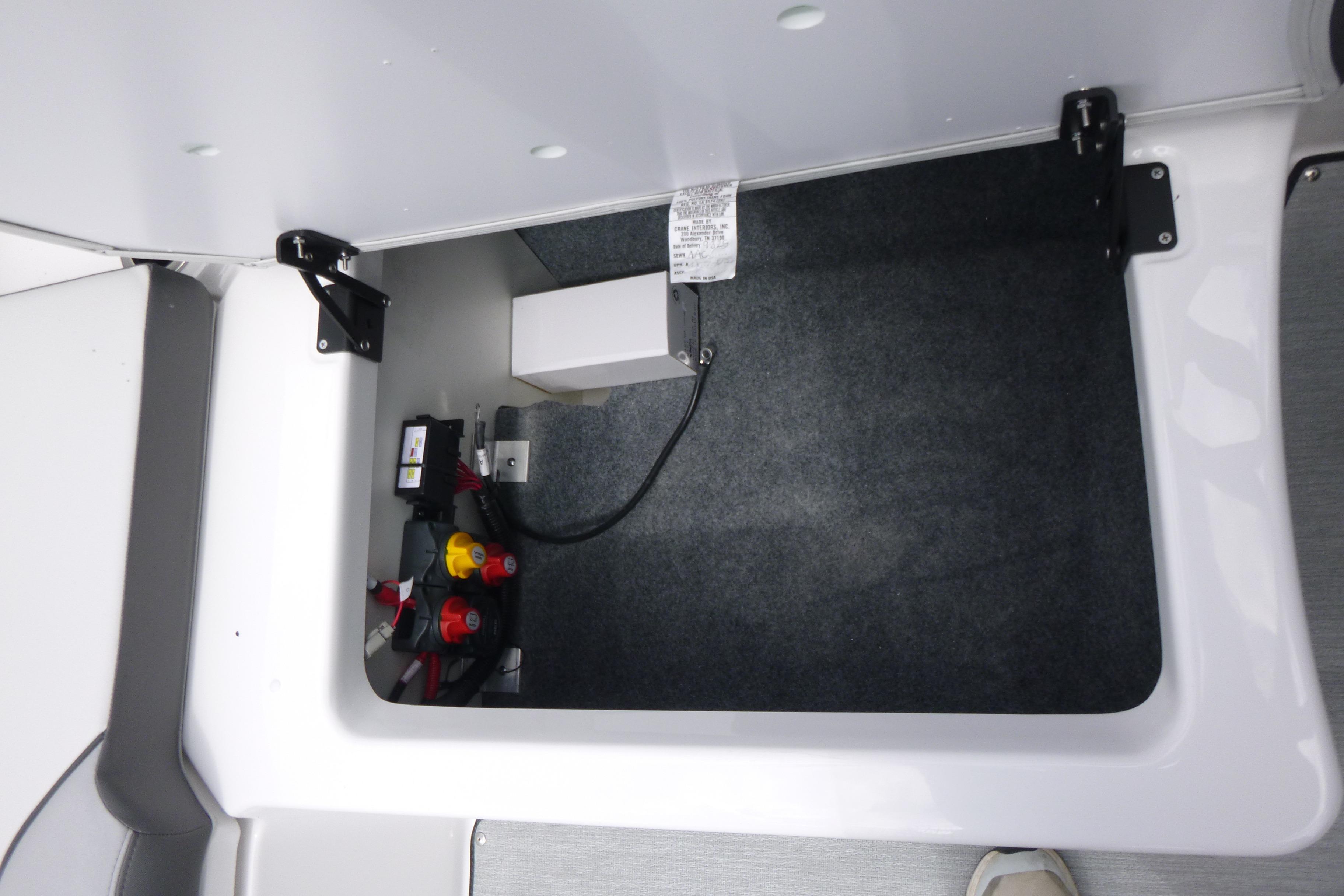2026 Yamaha Boats AR250 storage compartment with battery switches and wiring.