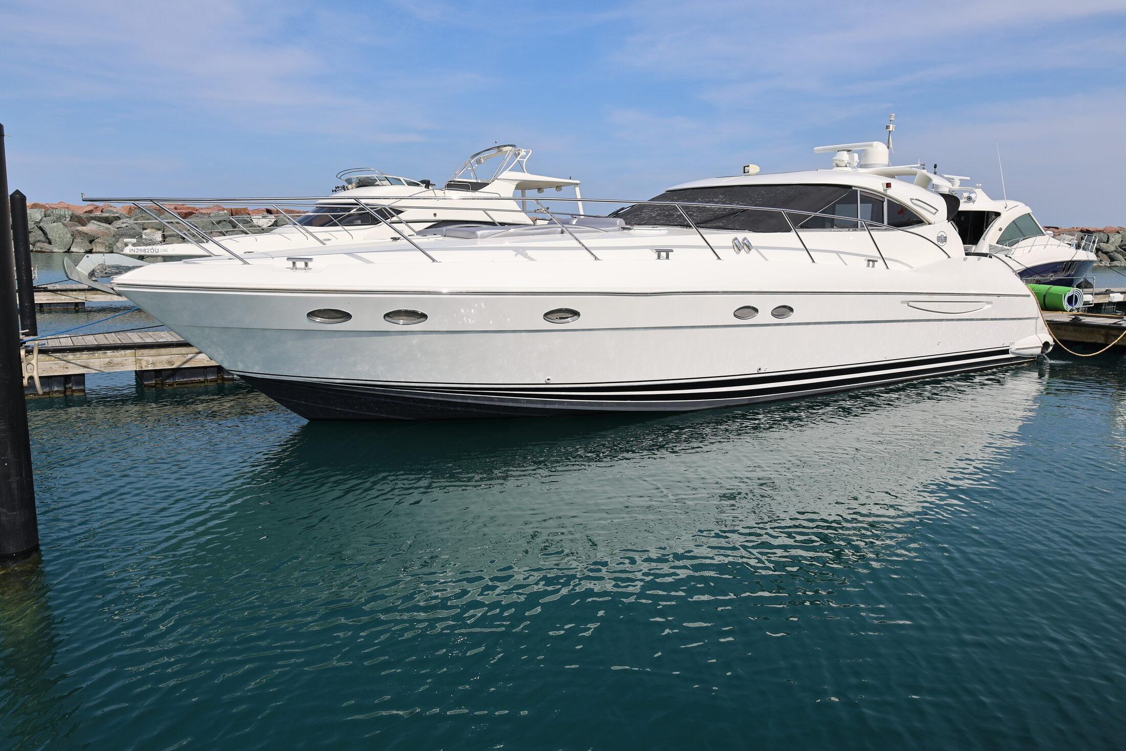 1999 Neptunus 54 Express yacht docked in a marina under a clear blue sky.