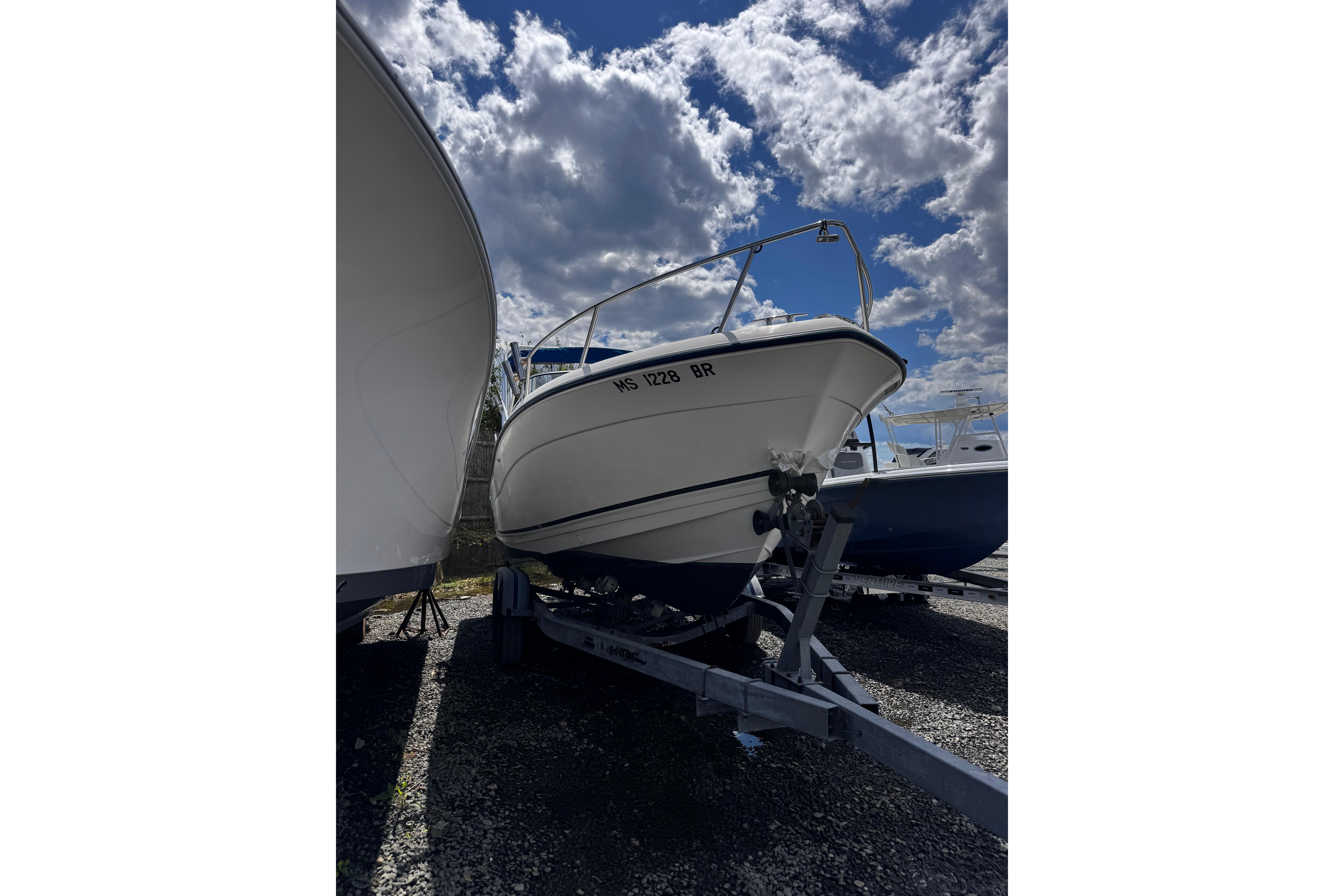 2003 Palm Beach 2200 Dual Console boat on trailer under cloudy sky.