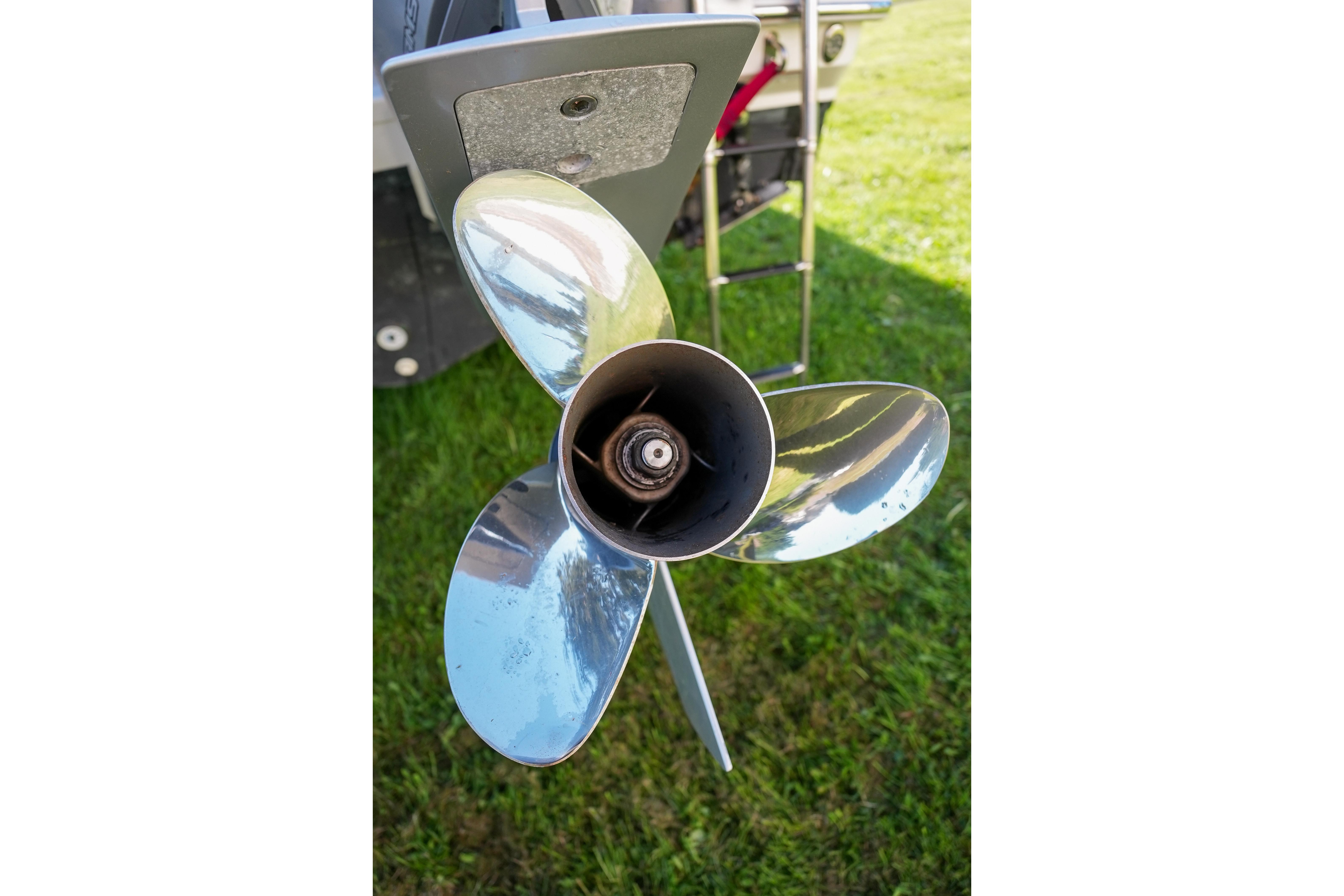 Shiny propeller of a 2019 Boston Whaler 286 Conquest boat on grass.