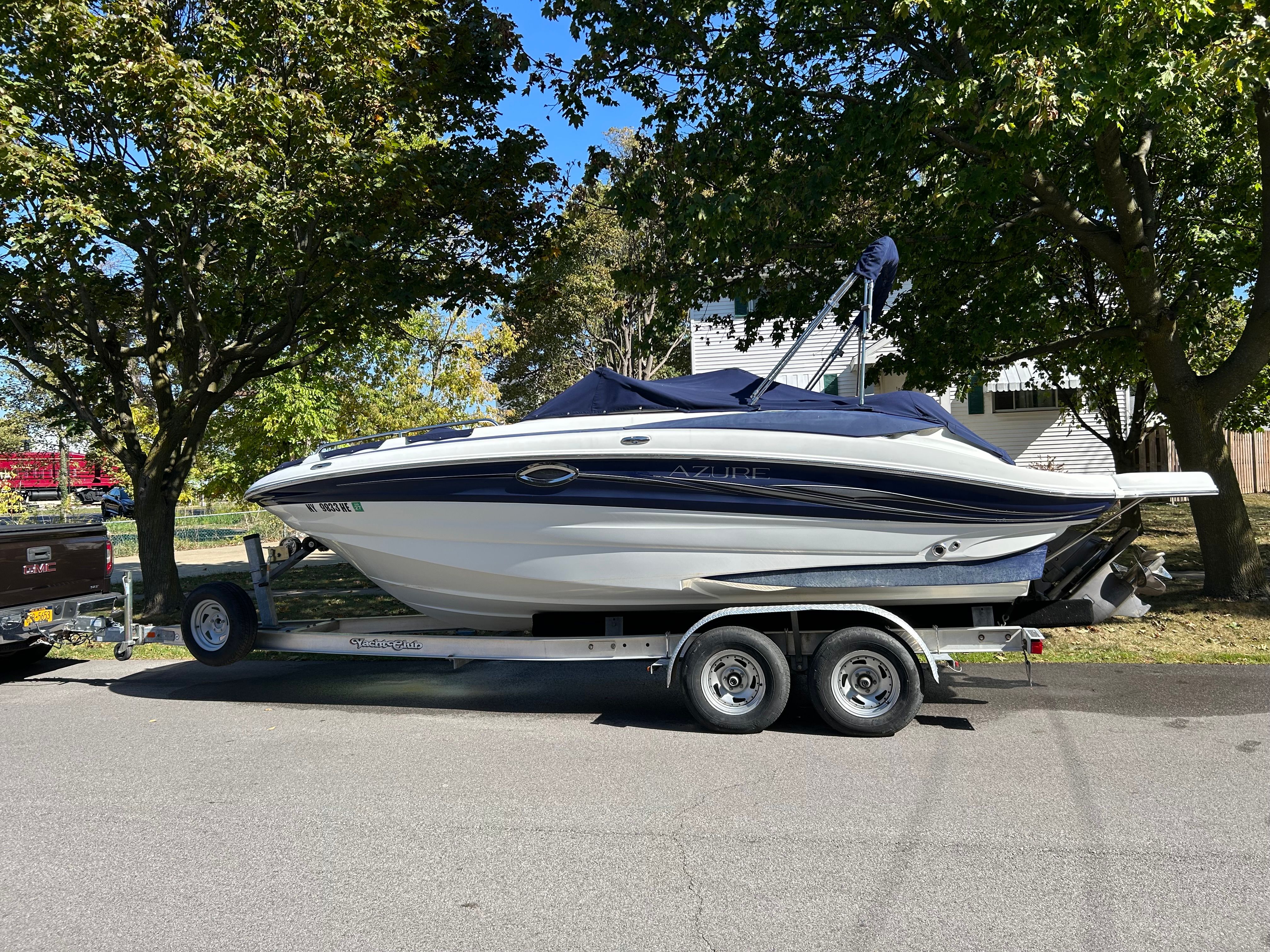 A 2008 Azure AZ220 boat on a trailer, surrounded by trees.