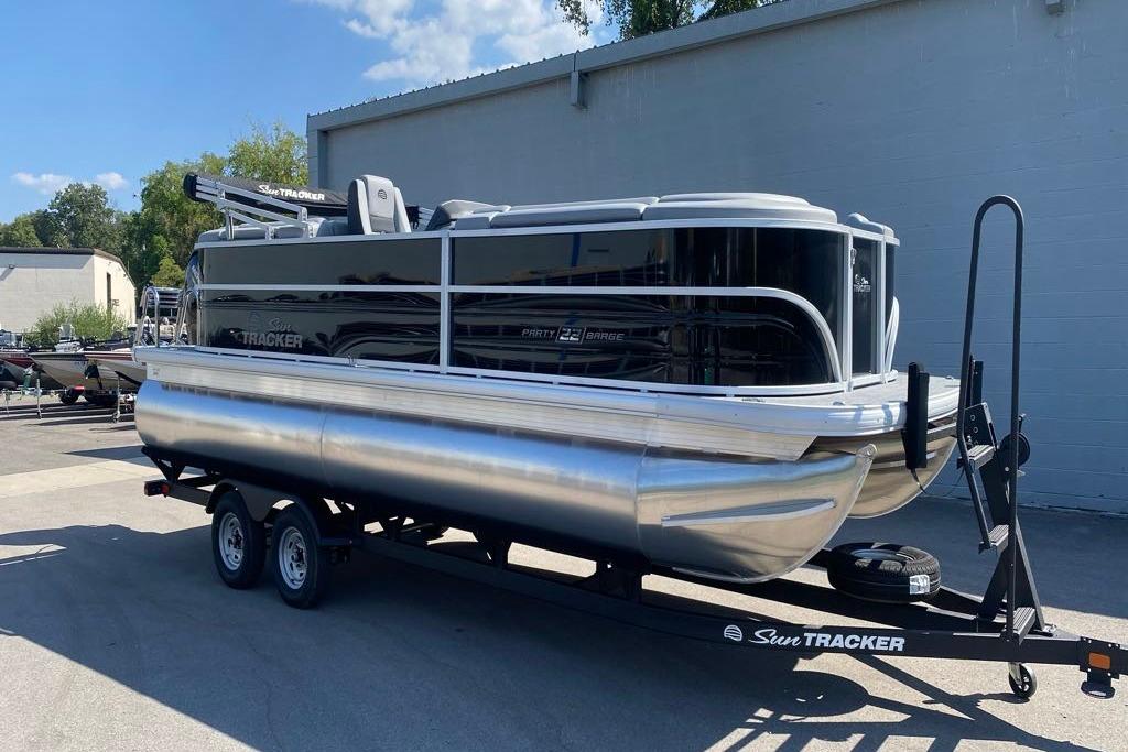 2026 Sun Tracker Party Barge 22 DLX pontoon boat on trailer, parked outdoors.
