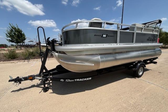 2026 Sun Tracker Bass Buggy 16 XL Select pontoon boat on trailer, parked outdoors.
