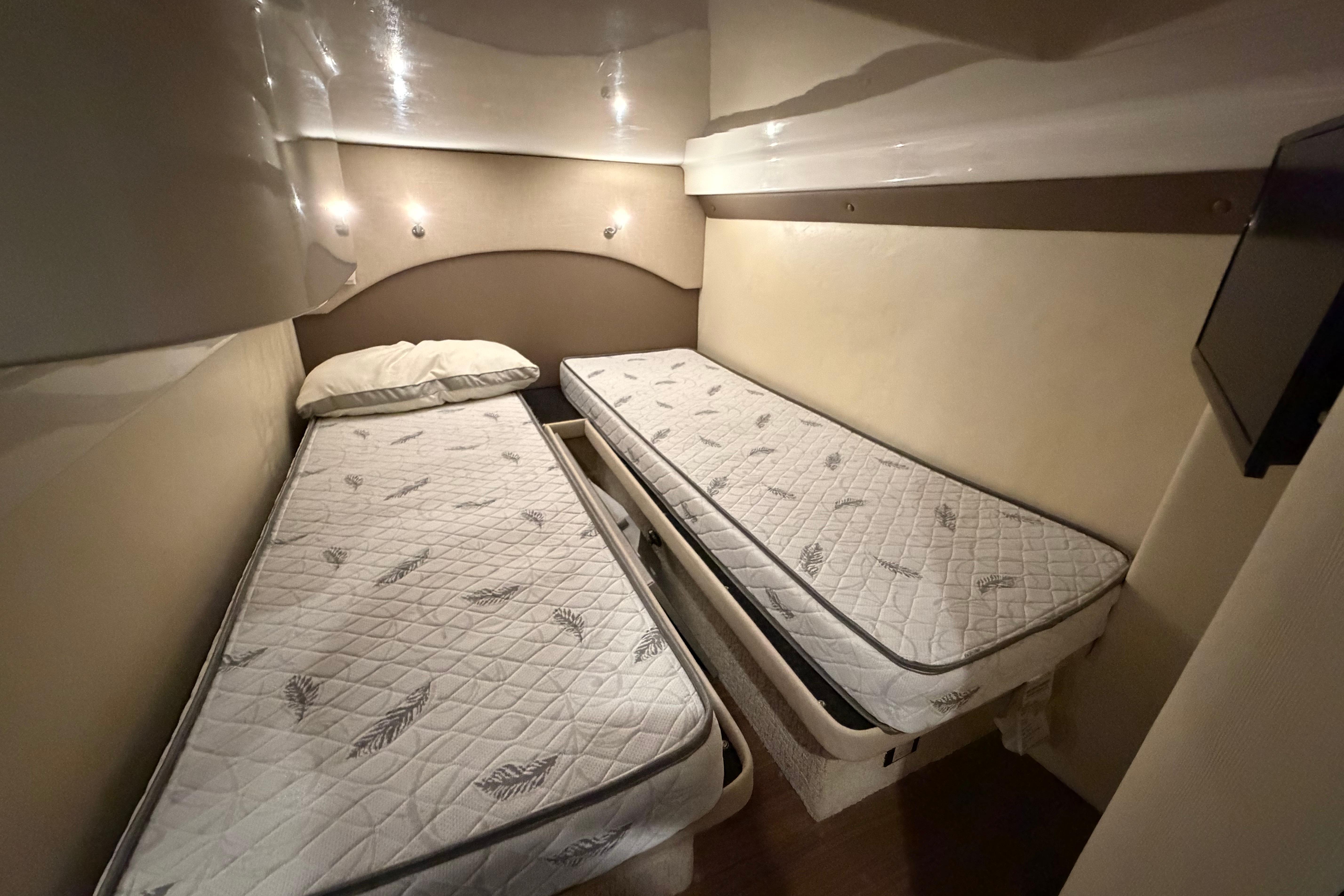 Twin beds in the 2018 Regal 42 Sport Coupe cabin, featuring cozy lighting and modern design.
