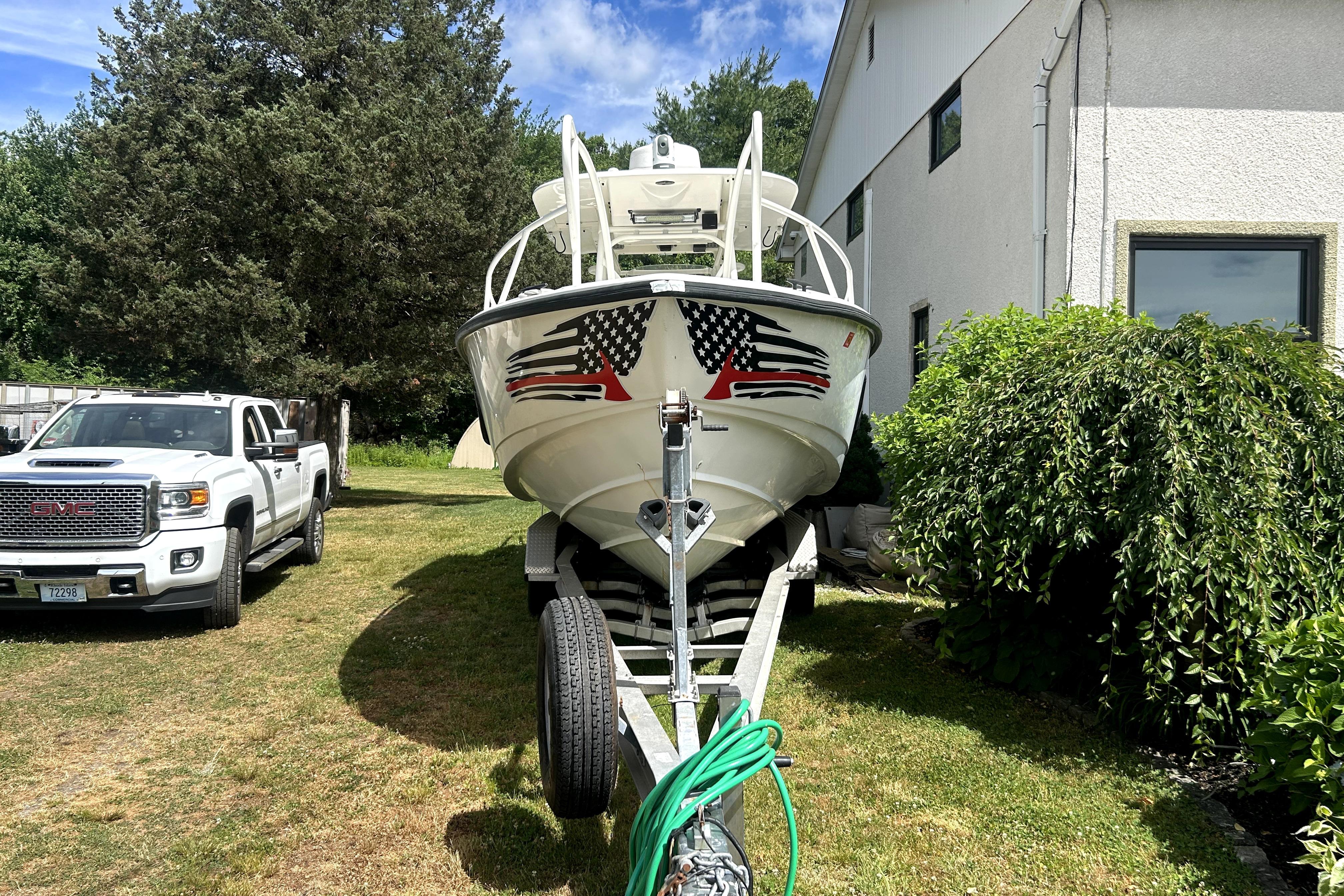 2012 Boston Whaler 320 Outrage on trailer beside white GMC truck, parked outdoors.