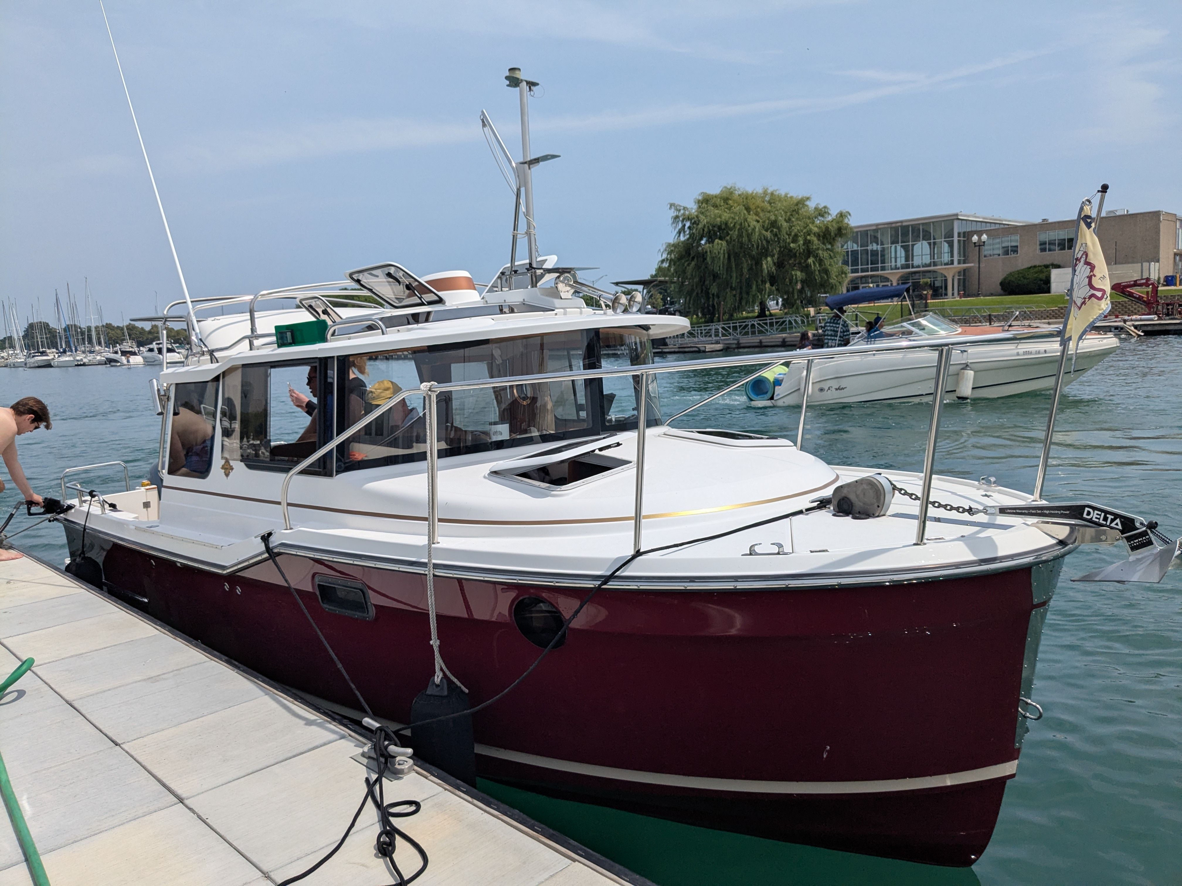 A red 2018 Ranger Tugs R-23 boat is docked. People are on board.