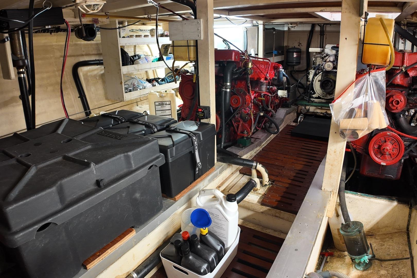Engine room of a 1978 Grand Banks 42 Classic boat, featuring red engines and storage containers.