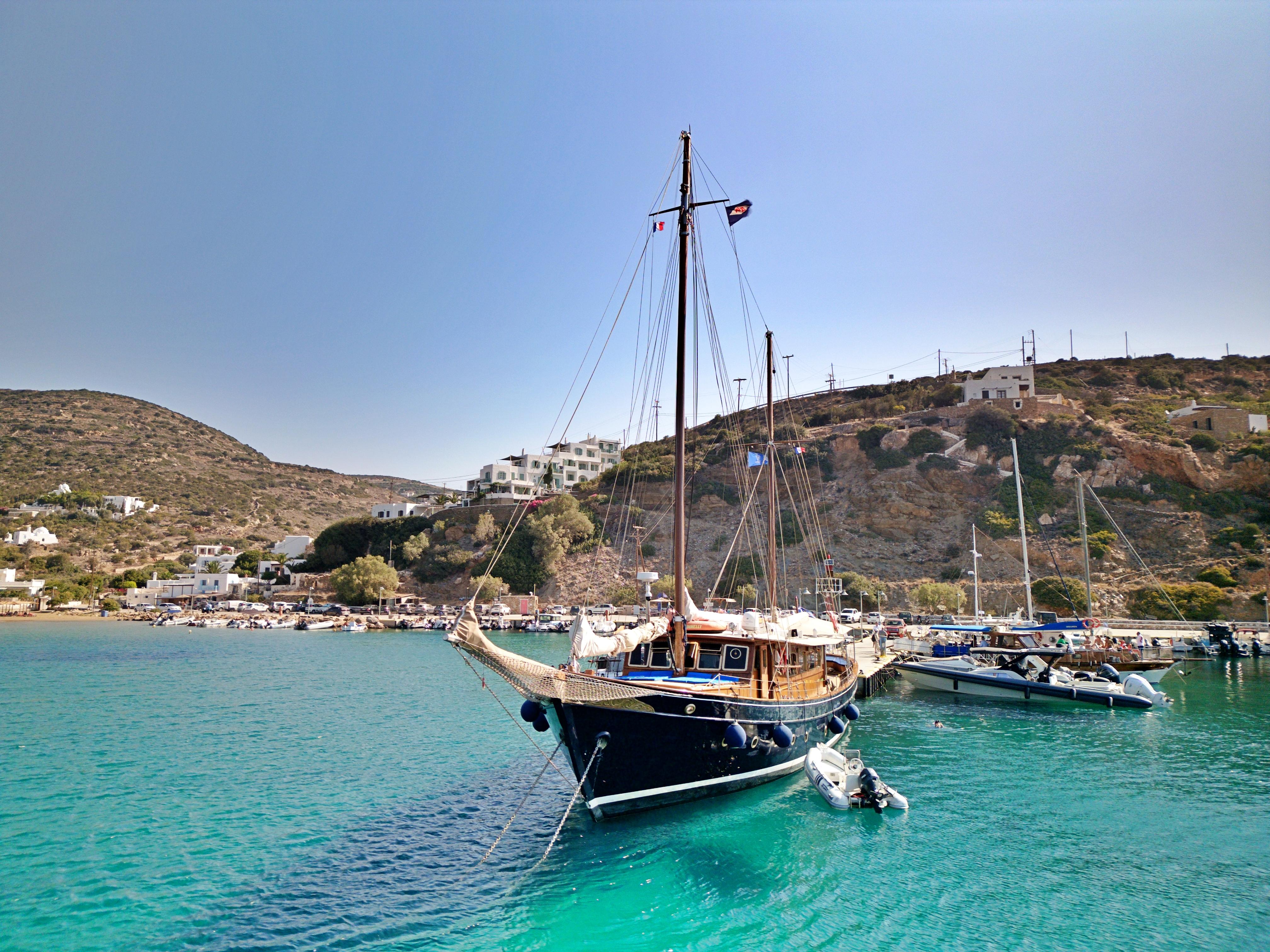 Vintage 1969 Psarros Shipyard boat anchored in clear turquoise waters, scenic coastal backdrop.