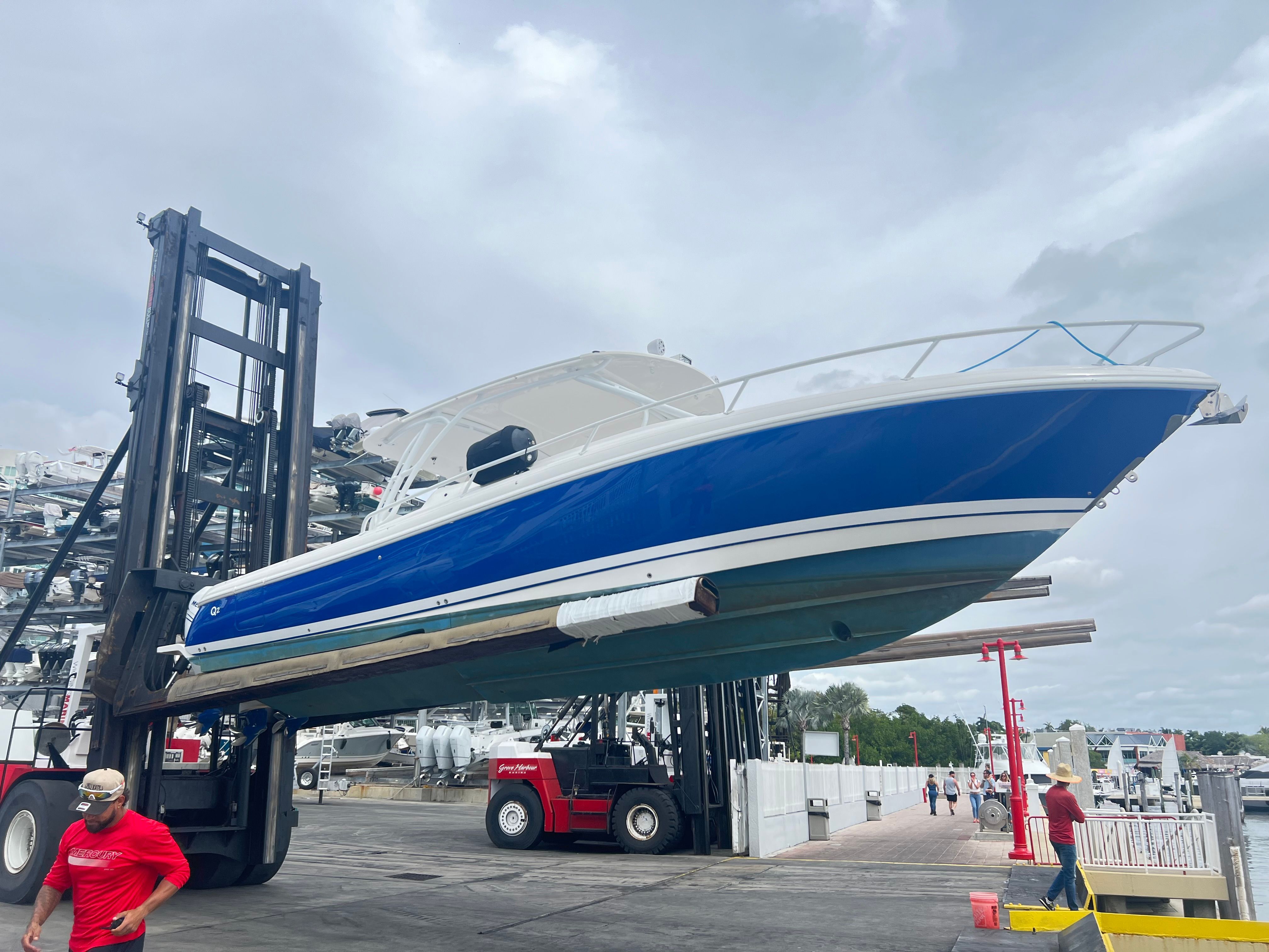 A blue and white 2014 Intrepid 375 Walkaround is lifted on land by a forklift.