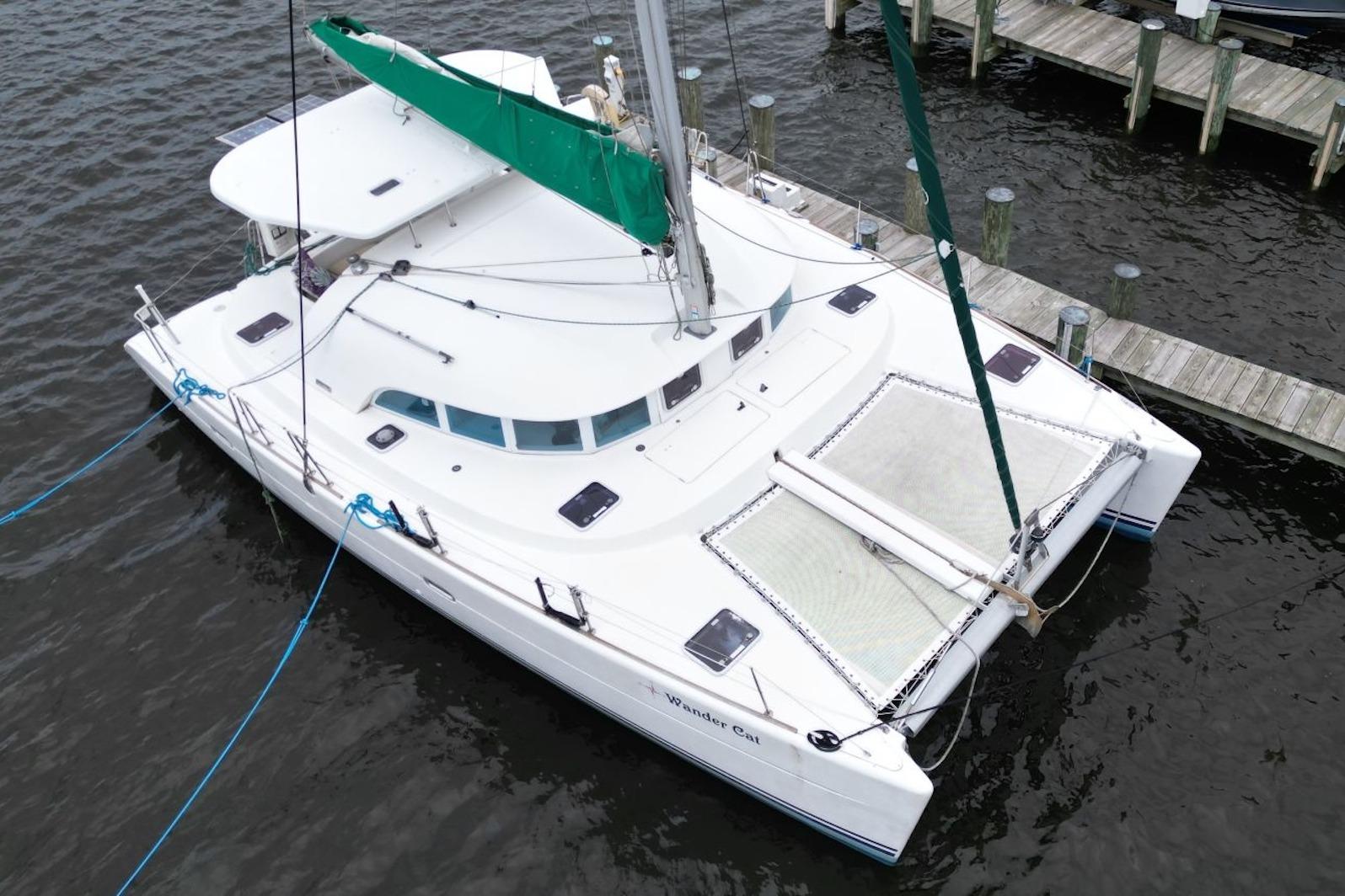 2004 Lagoon 380 catamaran docked, featuring white hull and green sail.