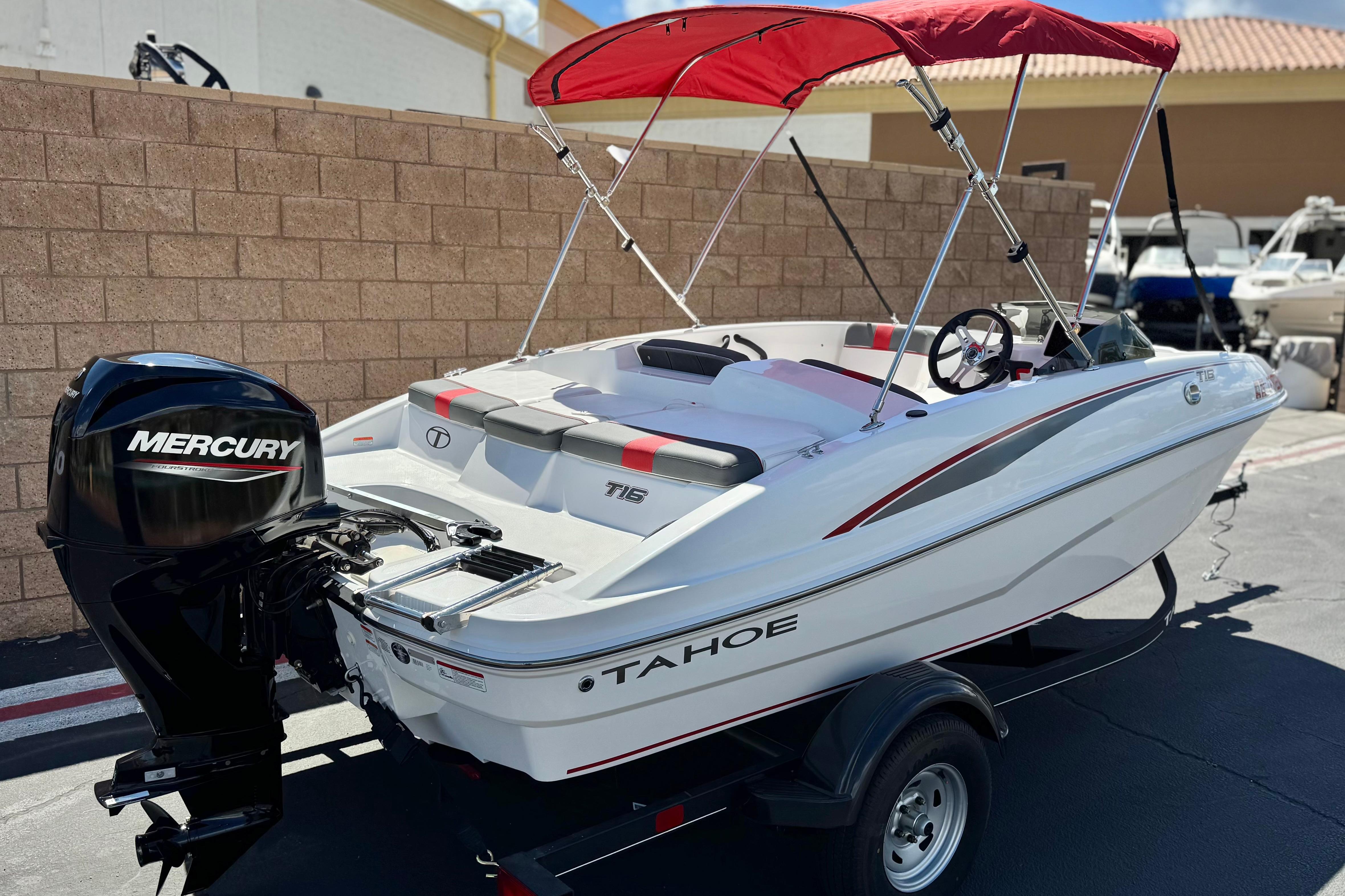 2024 Tahoe T16 boat with Mercury engine and red canopy, parked outdoors.