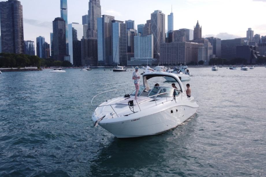 2008 Sea Ray 350 Sundancer cruising near city skyline with people on deck.