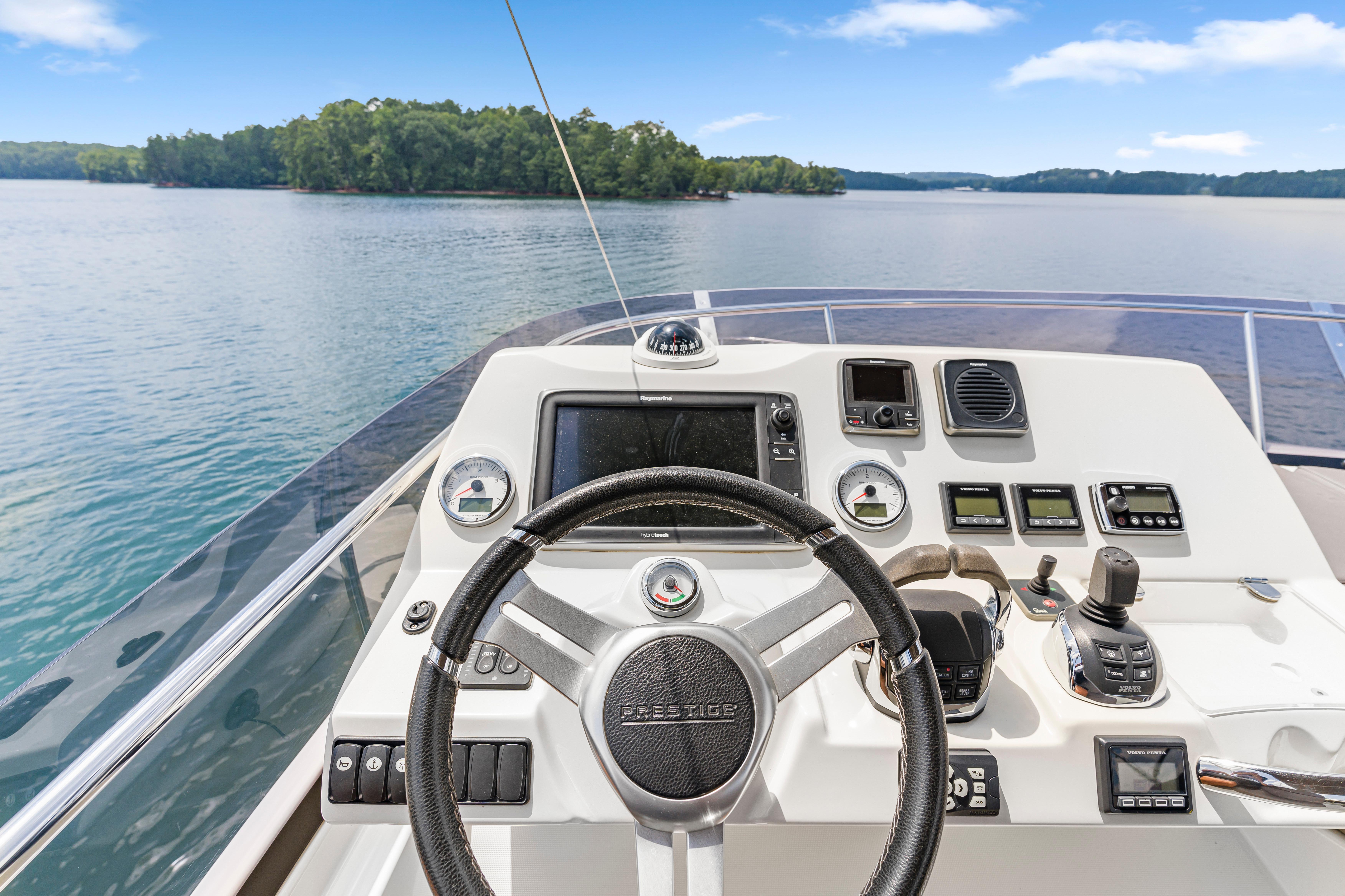 Helm of 2017 Prestige 500 yacht with scenic lake view.