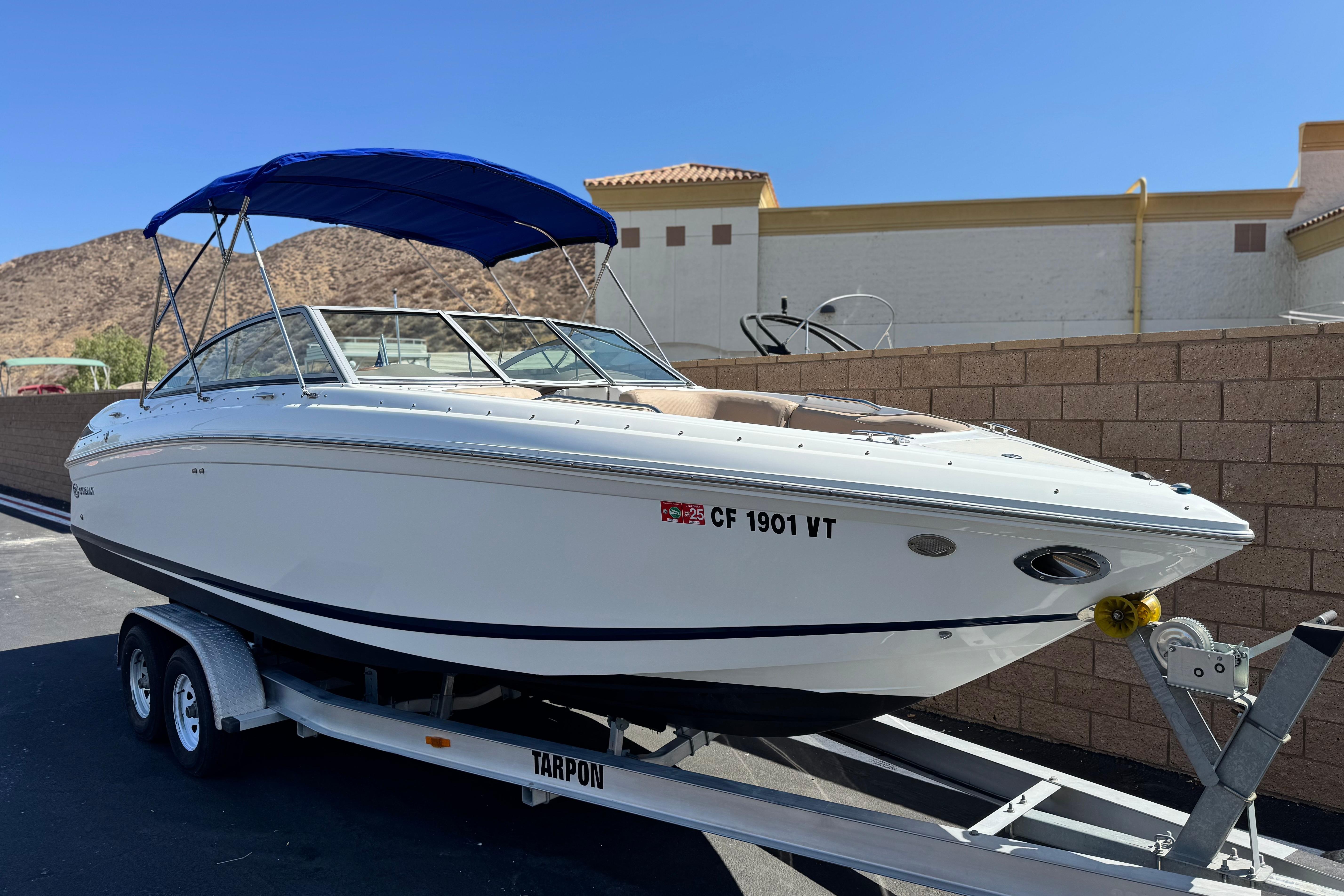 2008 Cobalt 262 boat on trailer with blue canopy, parked near brick wall.