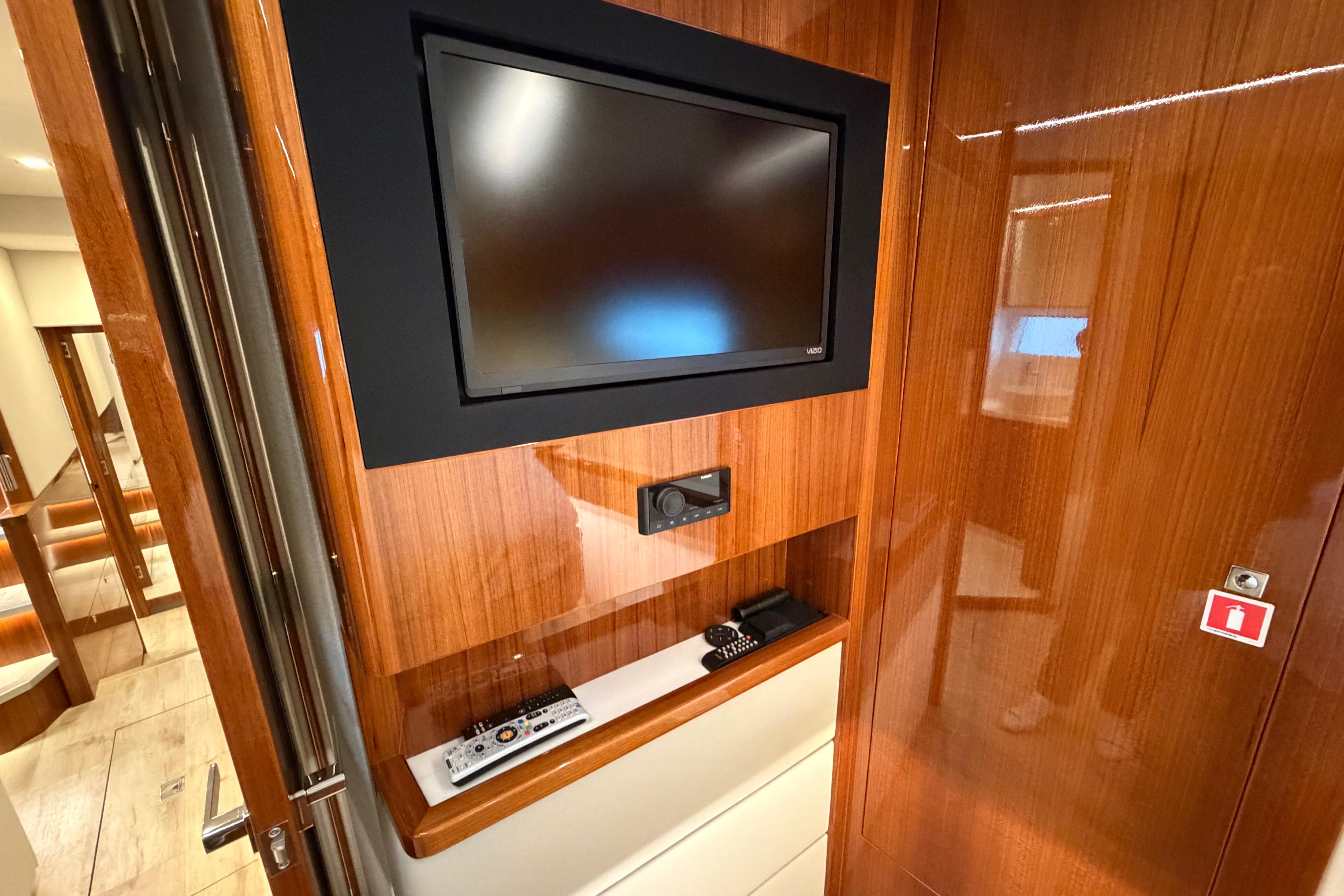 Luxurious interior of 2023 Riviera 645 SUV yacht with mounted TV and remote controls.