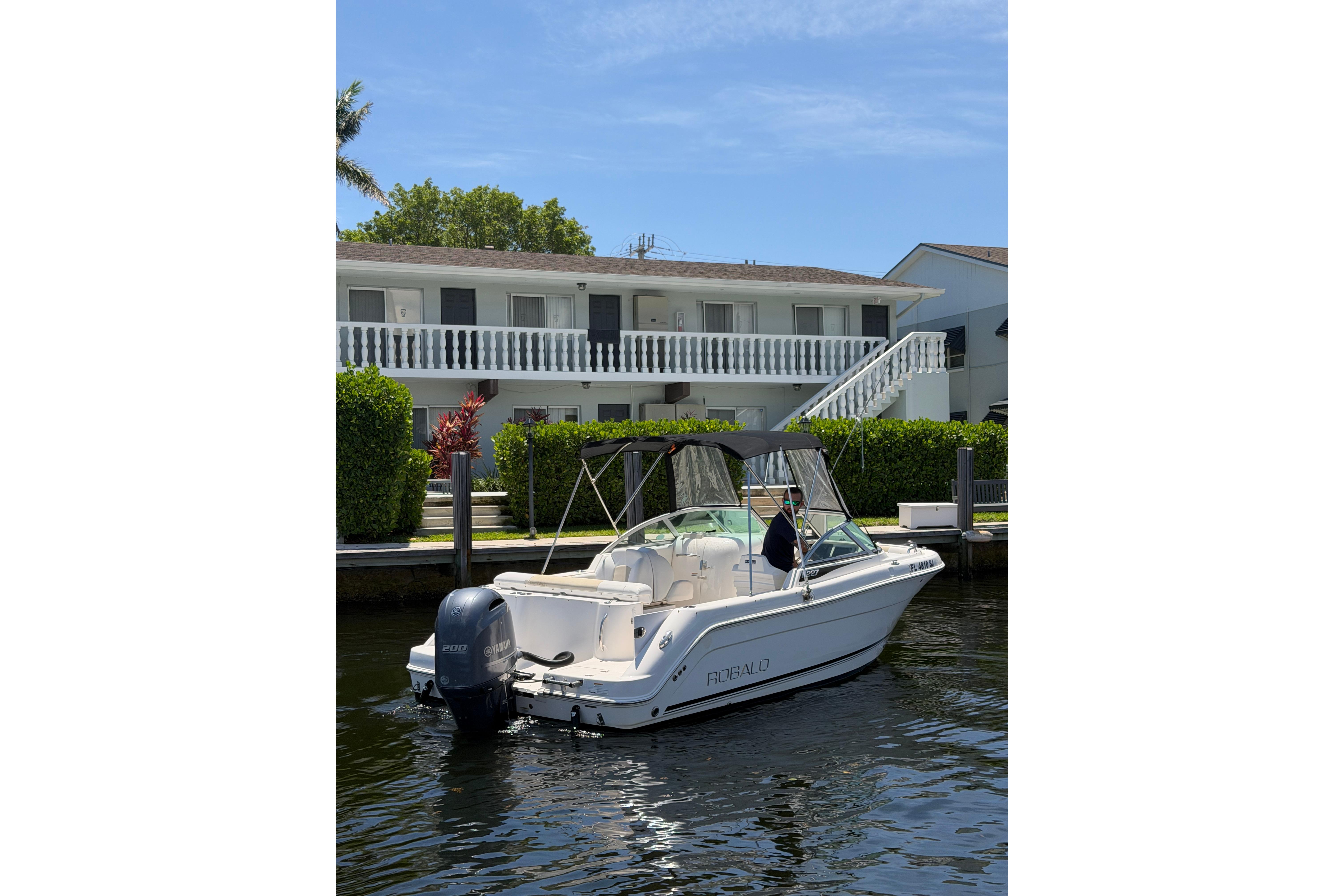2015 Robalo R227 Dual Console boat docked near waterfront property.