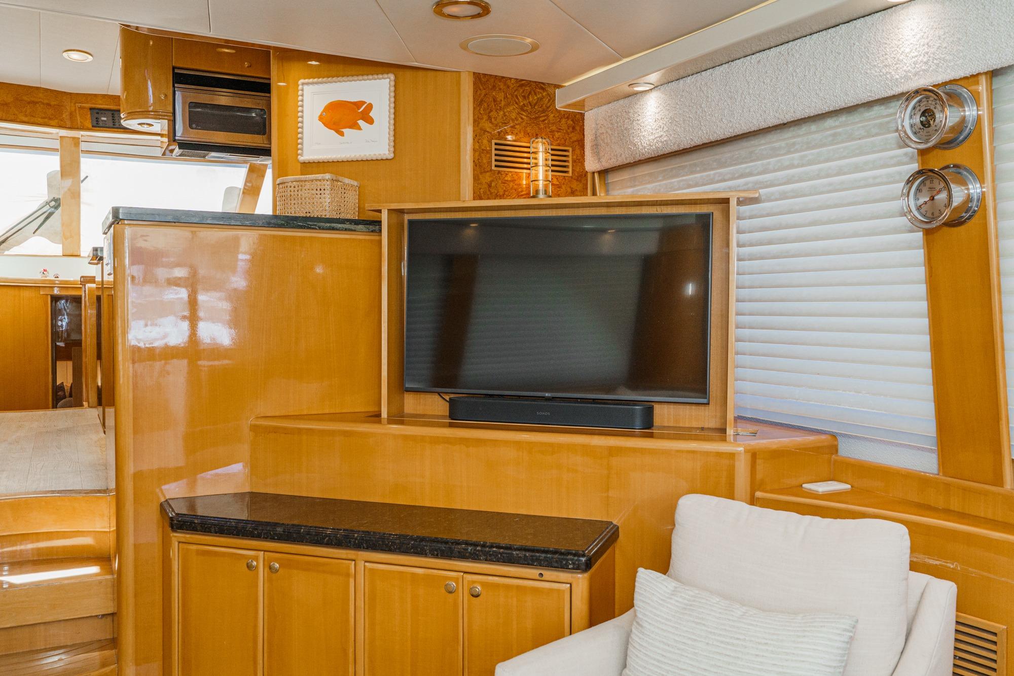 Luxurious interior of 2003 McKinna 65 Pilothouse yacht with TV and elegant wood finish.