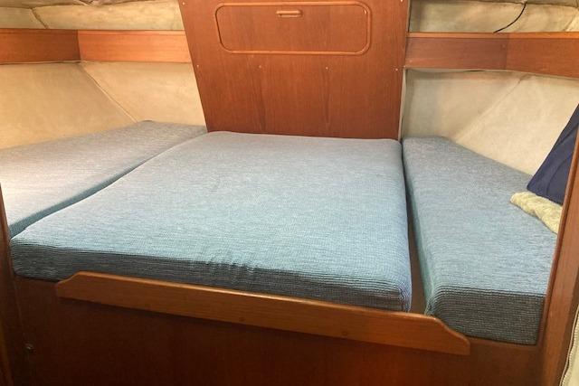 Cozy cabin berth in 1988 Westerly Corsair 36 sailboat with blue cushions.