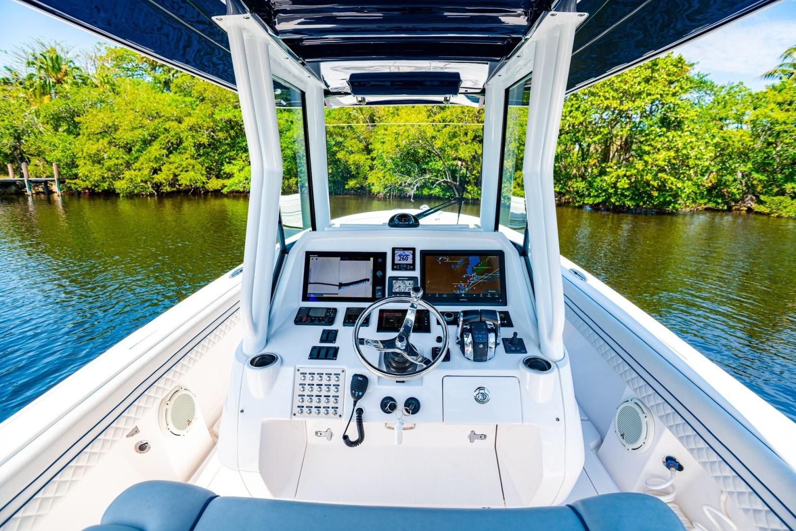 2018 Intrepid 327 Center Console boat cockpit with navigation screens, steering wheel, and lush waterway view.