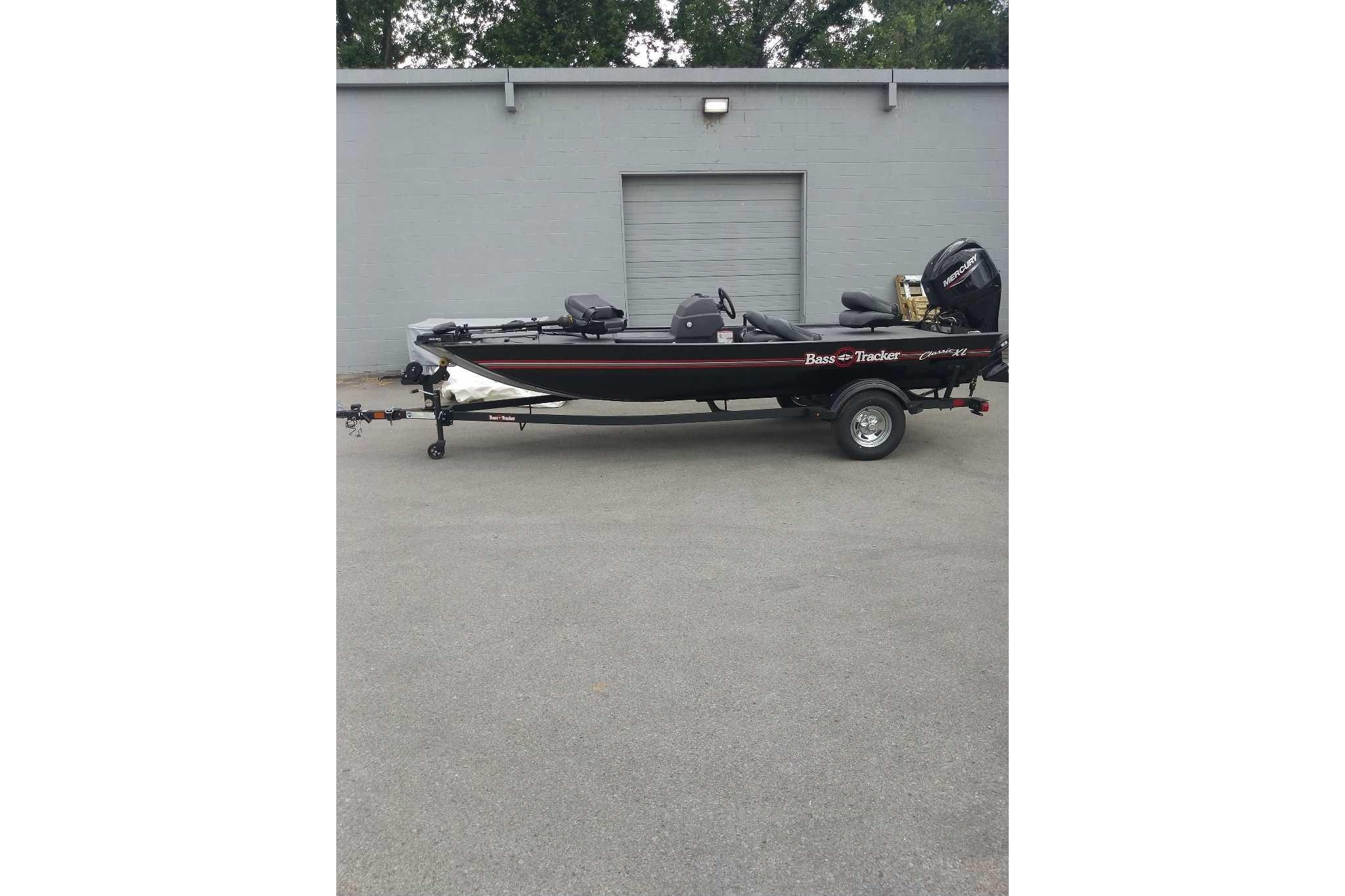 2026 Tracker Bass Tracker Classic XL boat on trailer, parked outside a gray building.