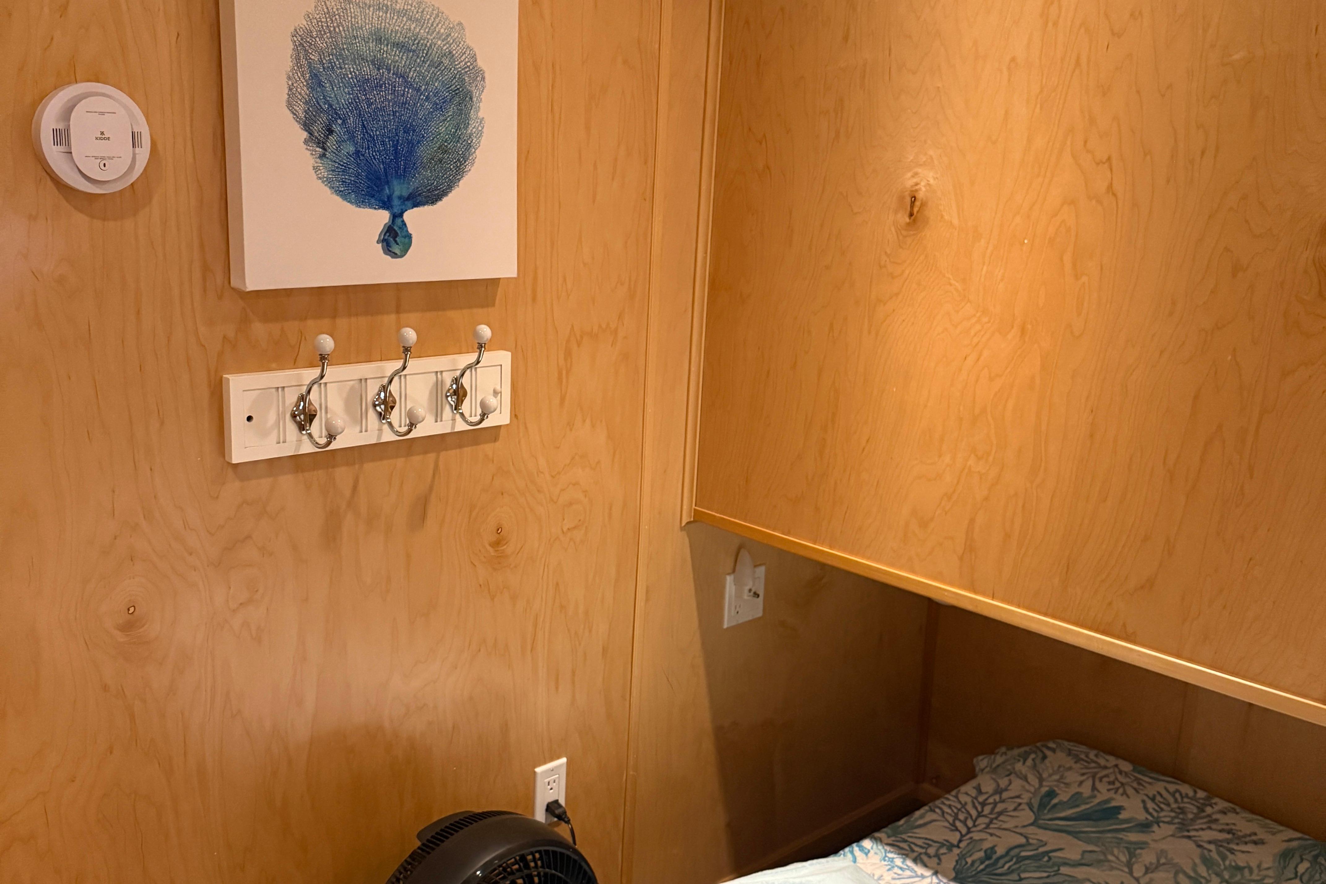 Wooden room interior with wall art, coat hooks, and bedding, STARDUST Oceans Share #2, 2015.