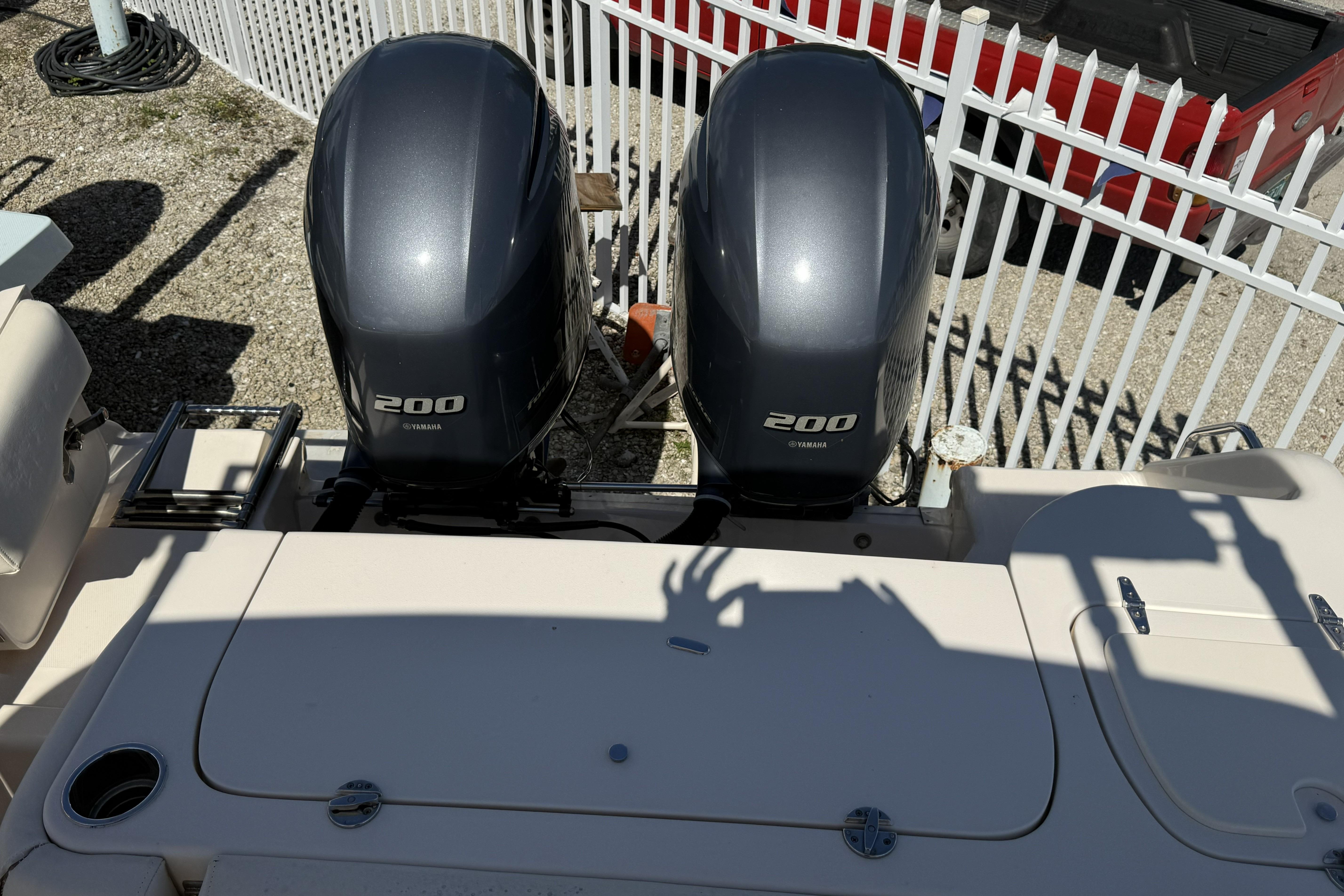 2014 Grady-White Freedom 275 boat with twin Yamaha 200 engines, parked near a white fence.