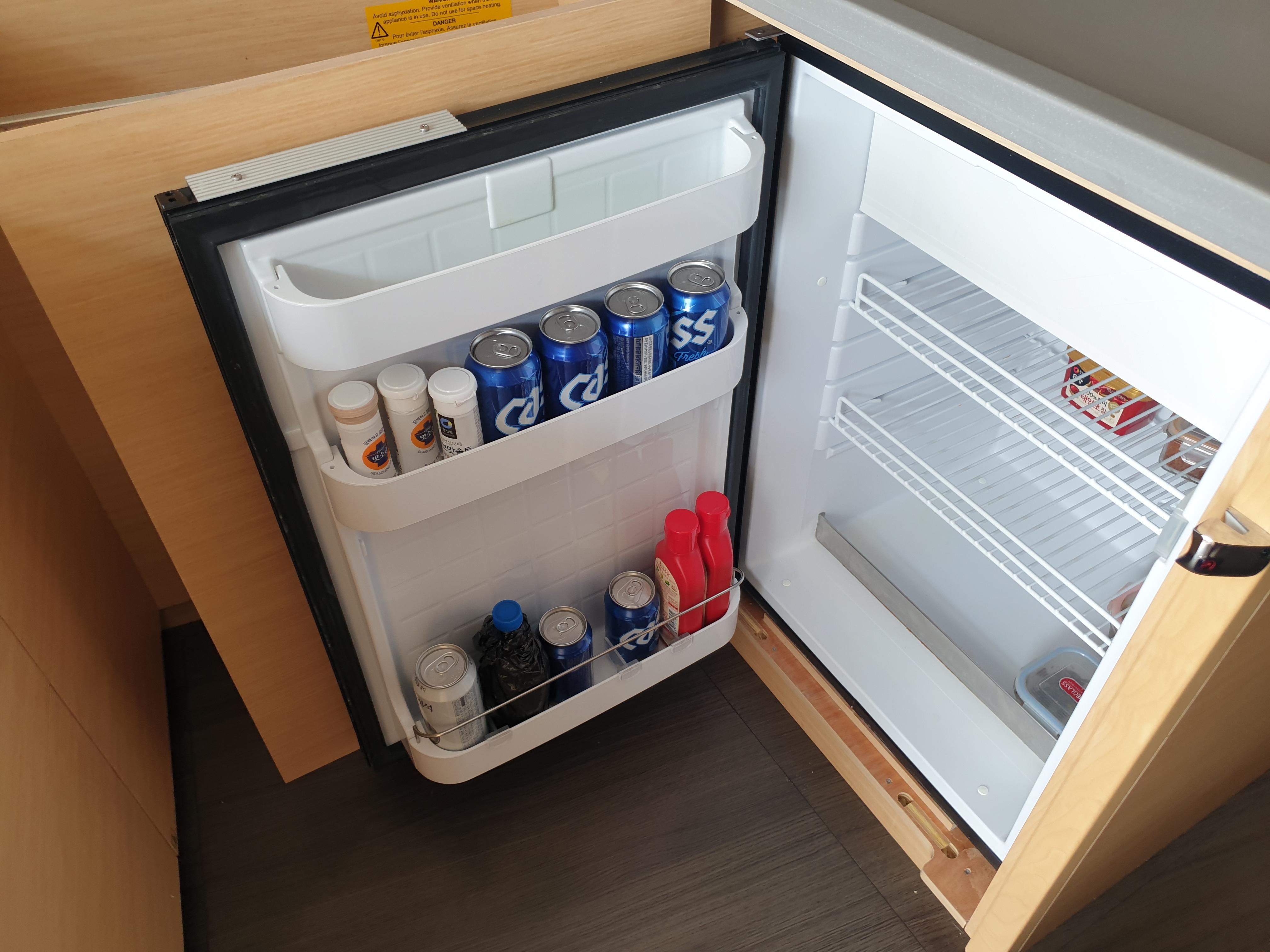 Open mini fridge in Lagoon 450S yacht, stocked with drinks and snacks.