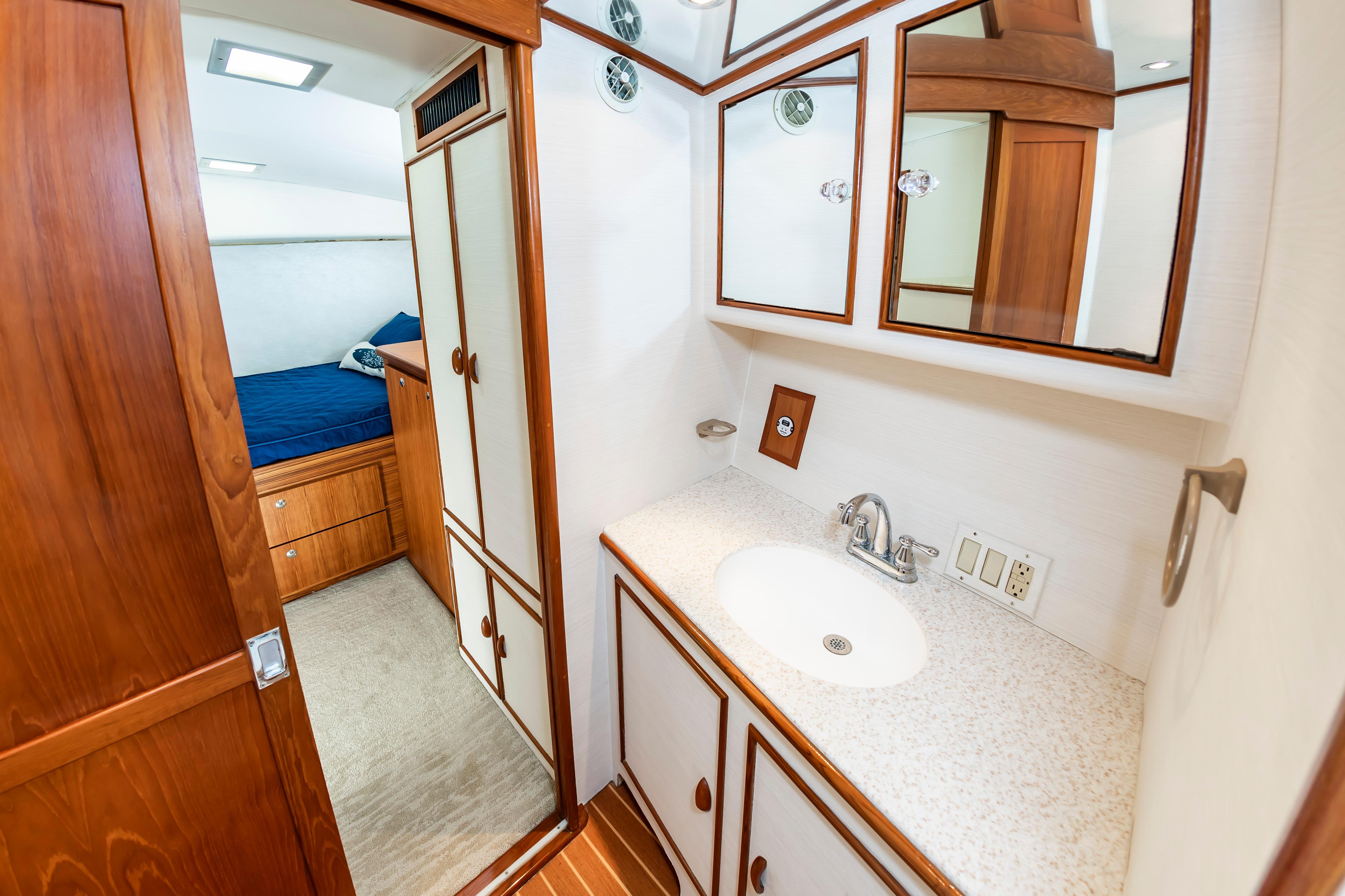 Bathroom interior of 1993 Custom Carolina Scarborough 56 Convertible yacht, featuring wood cabinetry and sink.