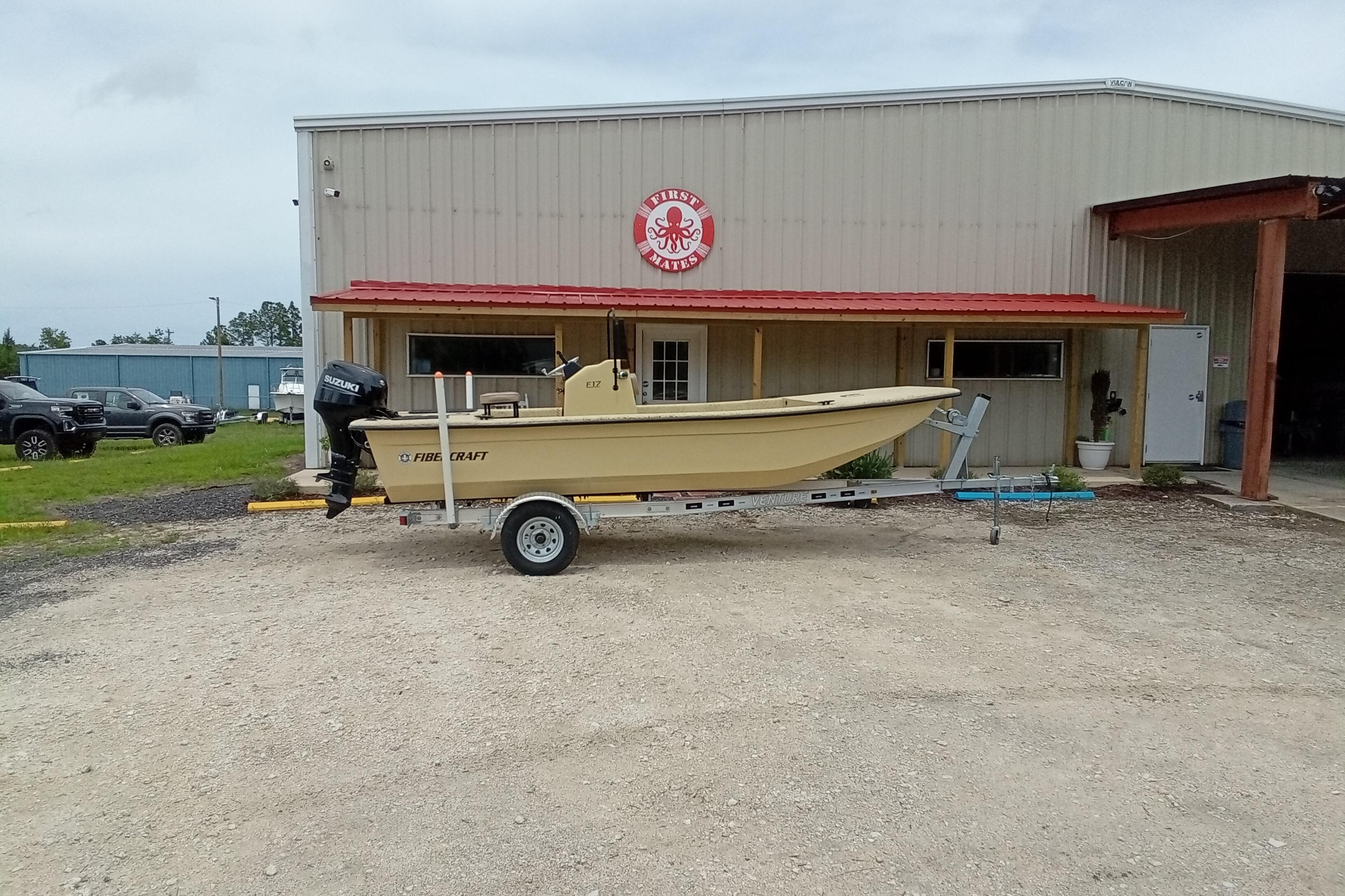 2025 Fibercraft F17 boat on trailer outside a metal building with red roof.