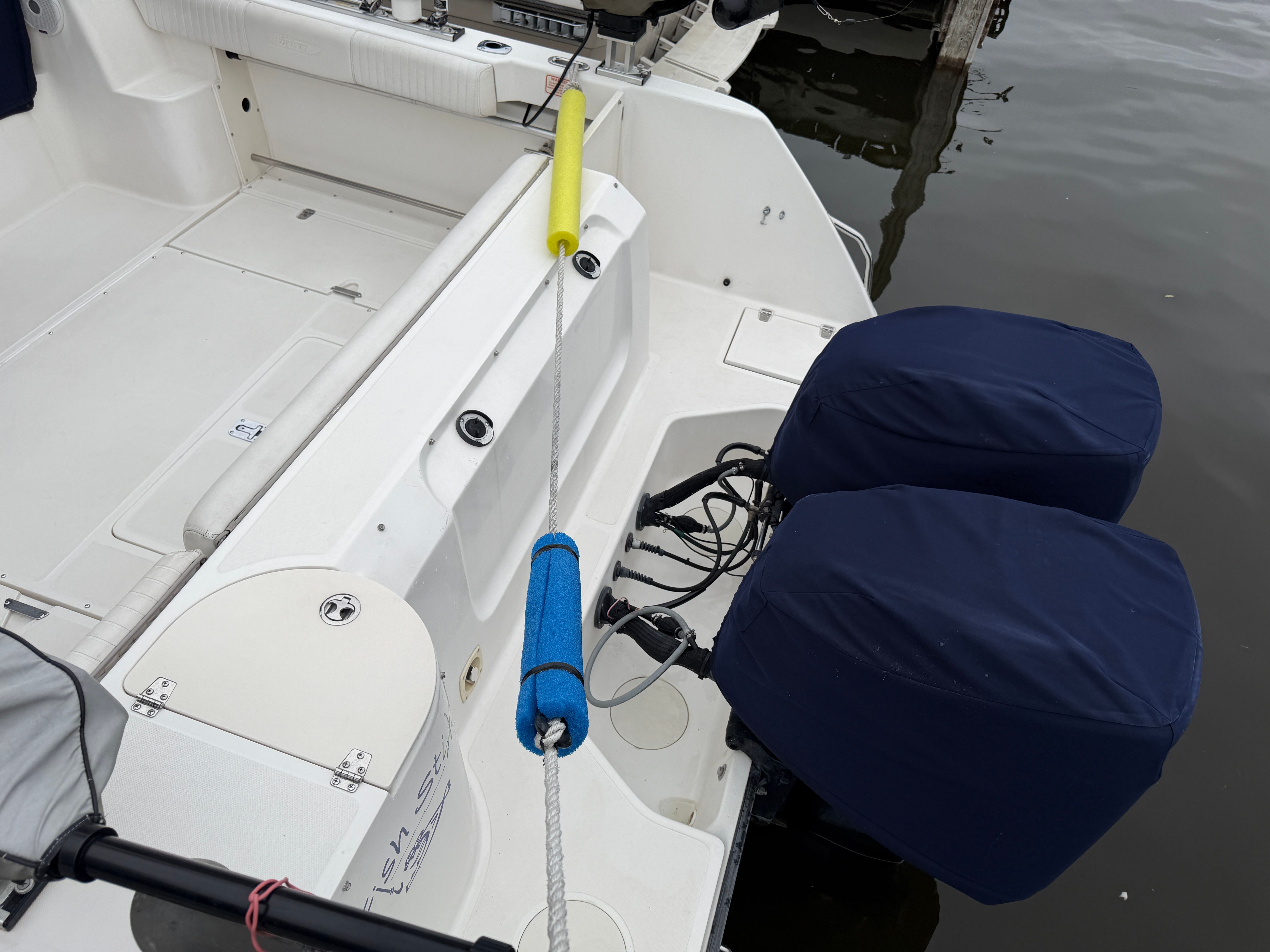 The image shows the stern of a Boston Whaler 26 Conquest boat with two covered engines.