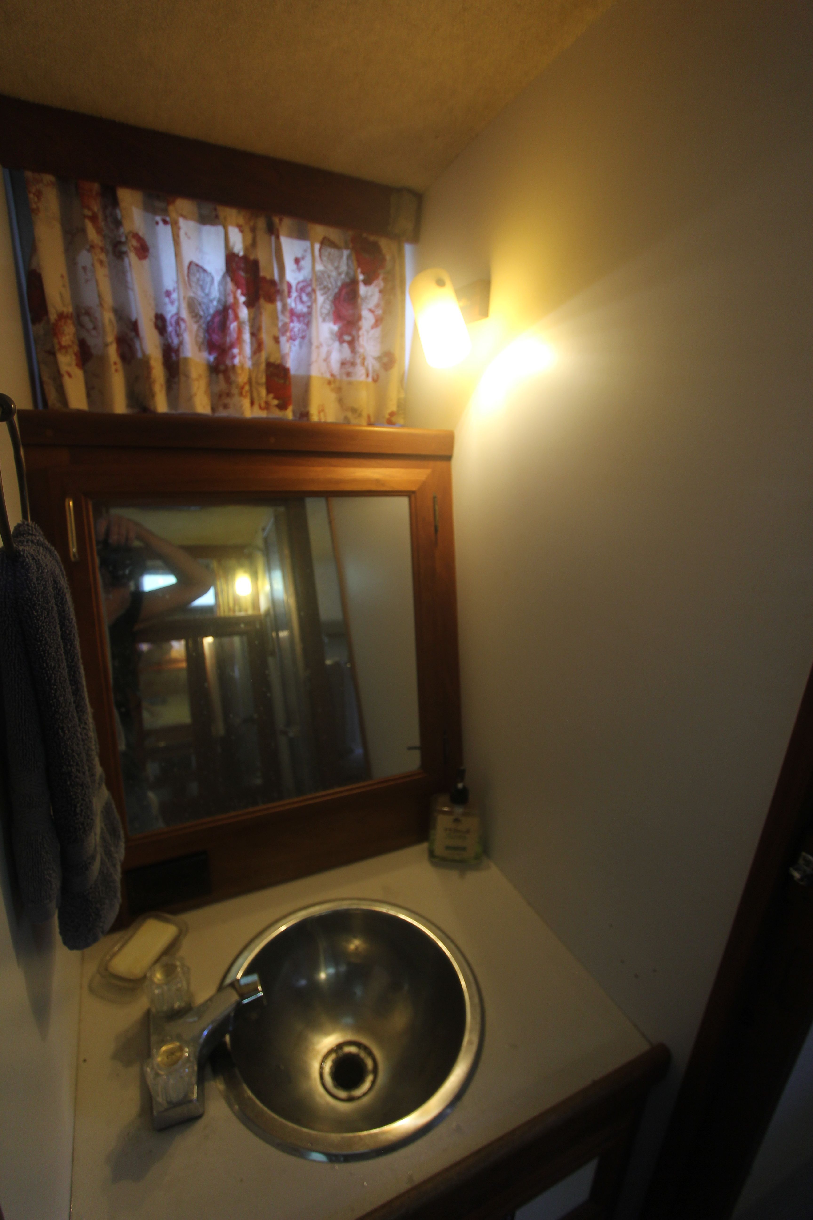 A bathroom with a round sink, mirror, and curtain. Soft lighting.