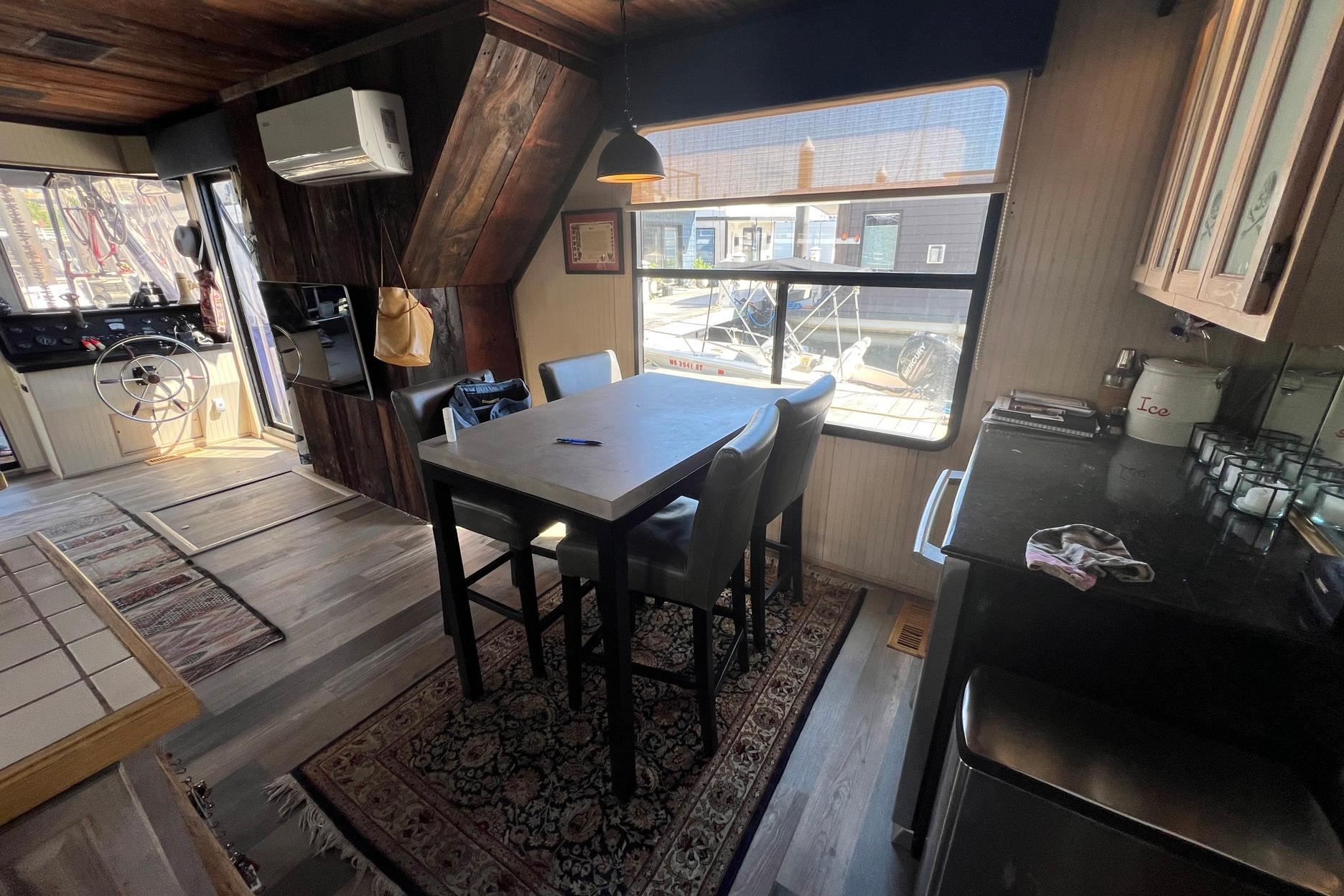 Interior of a 1993 Sumerset houseboat with dining area and helm, featuring rustic wood accents.
