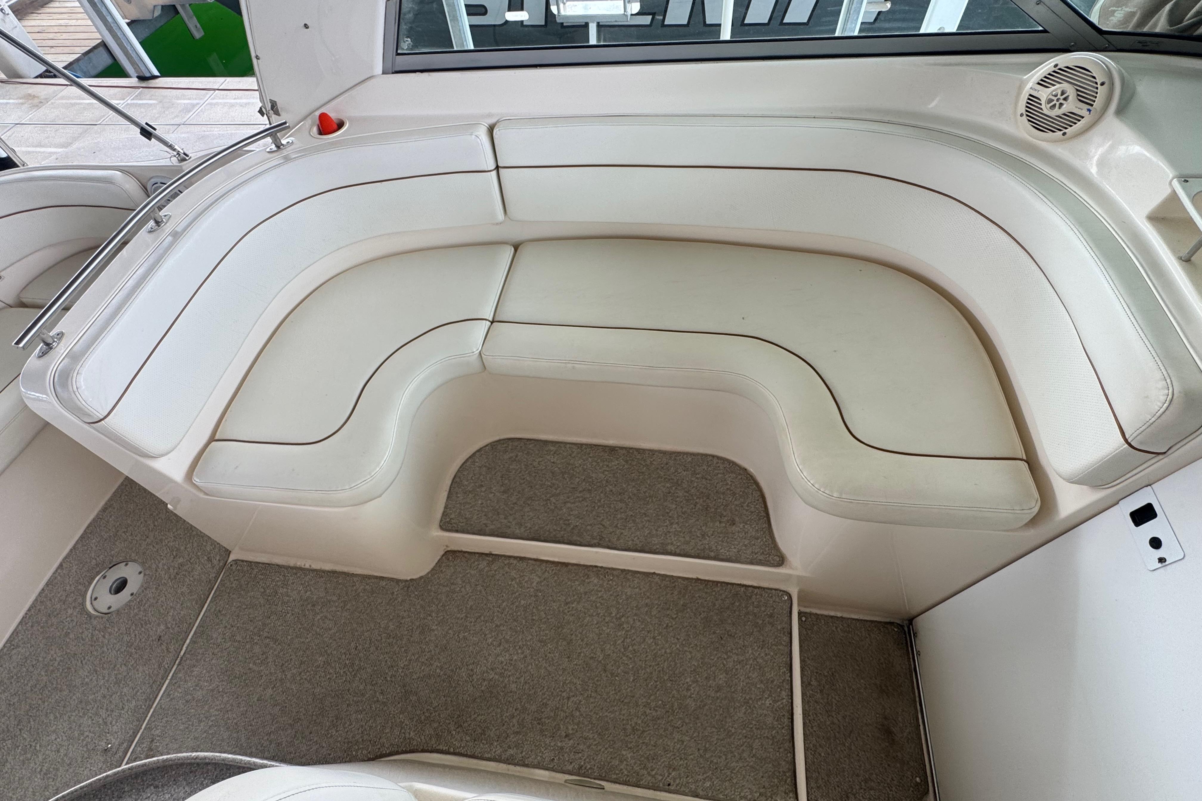 2004 Rinker Fiesta Vee 312 boat interior with white cushioned seating and carpeted flooring.