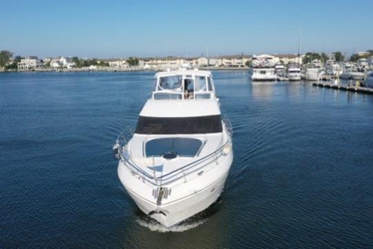 2005 Neptunus 56 Flybridge yacht cruising in a marina with clear skies.