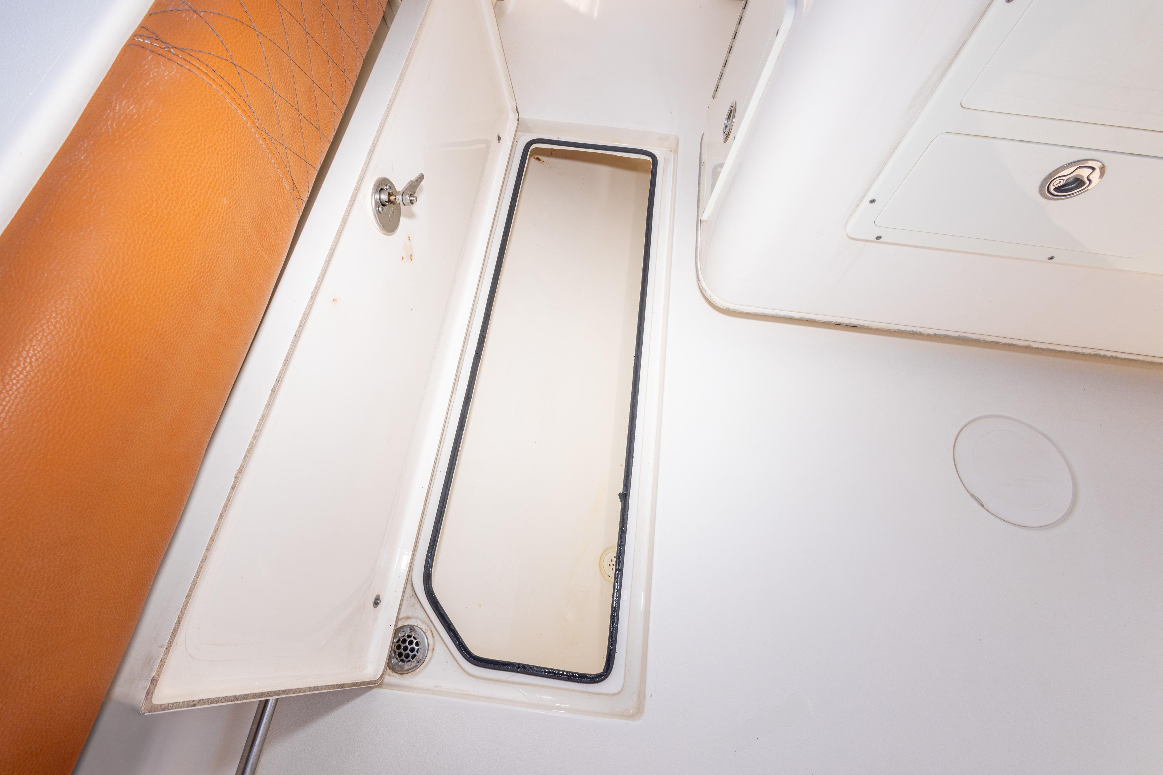 2017 Cobia 261 Center Console storage compartment with tan cushion and white interior.