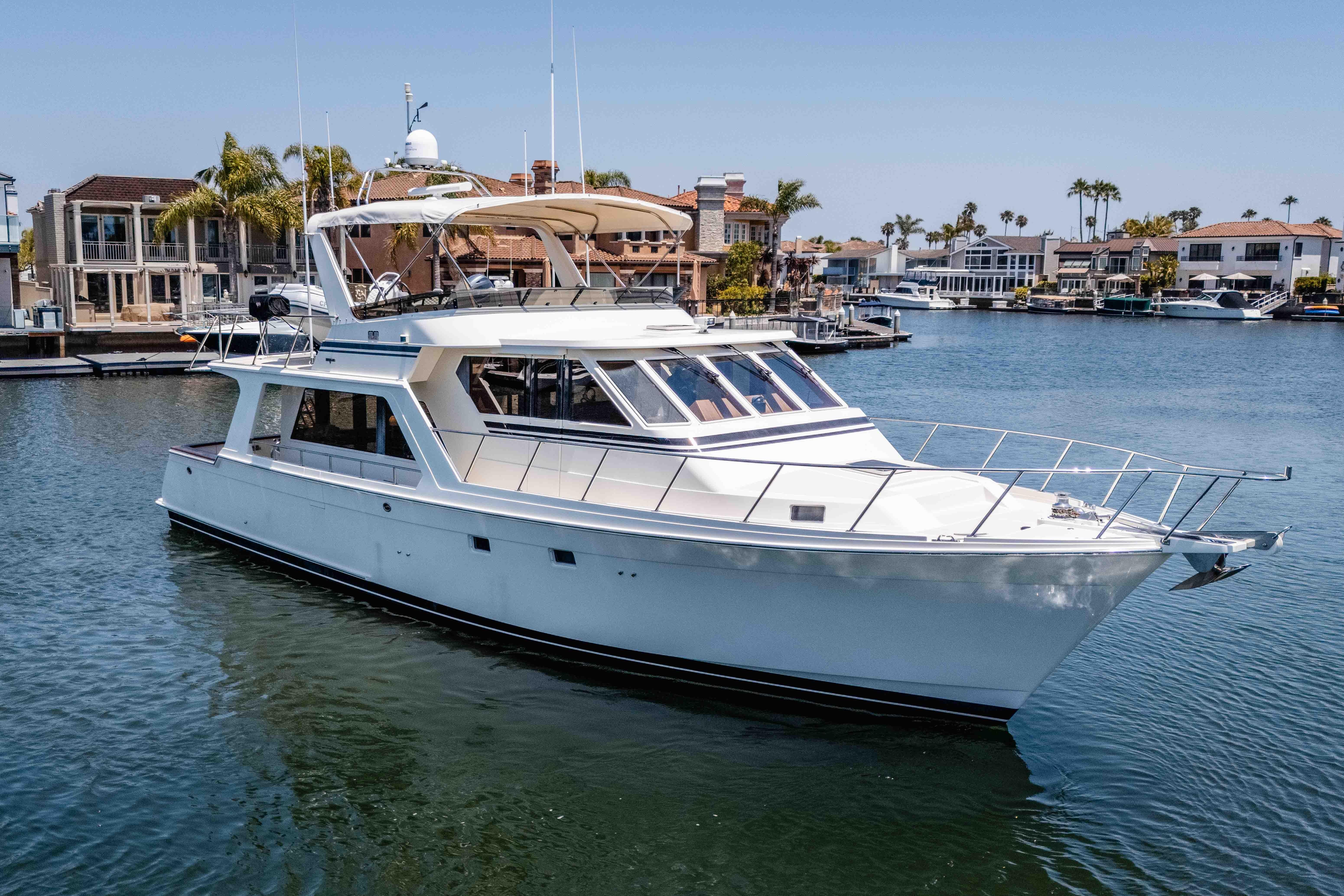 2005 Offshore Yachts 54 Pilothouse cruising in a marina with waterfront homes.