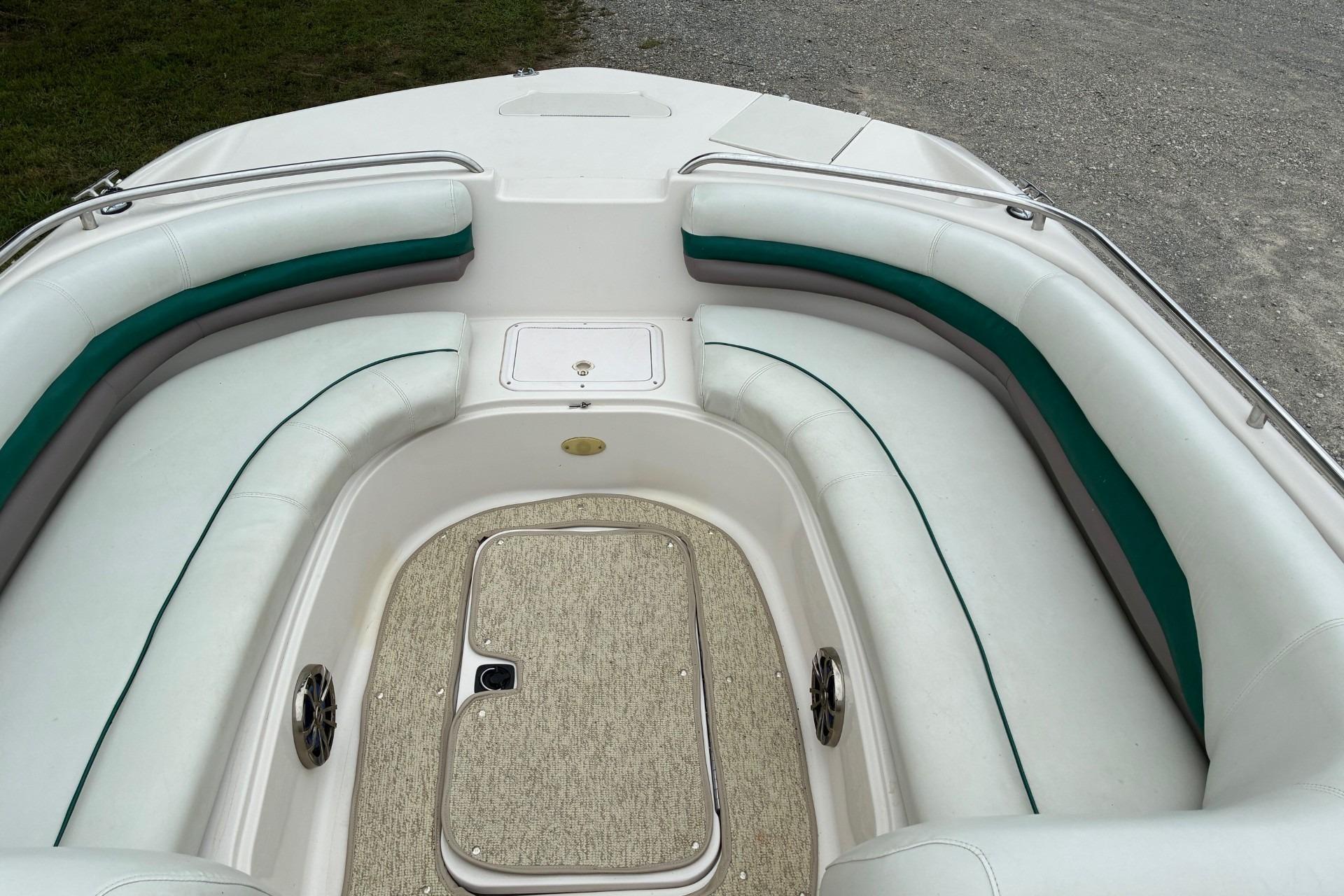 2003 Hurricane 234 SD boat interior with white and green seating, carpeted floor, and storage compartment.