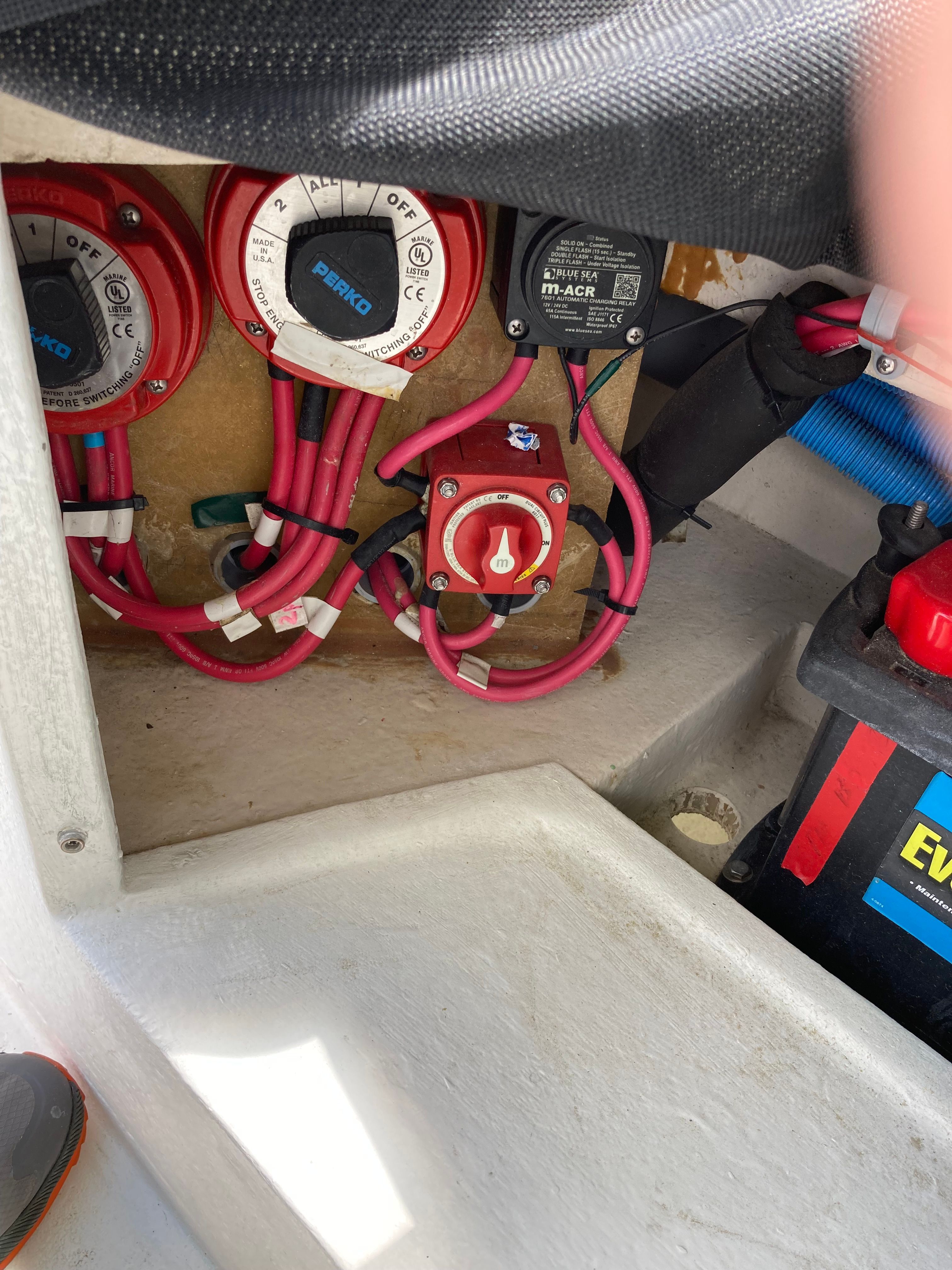 Electrical wiring and switches in a boat, featuring batteries and cables.