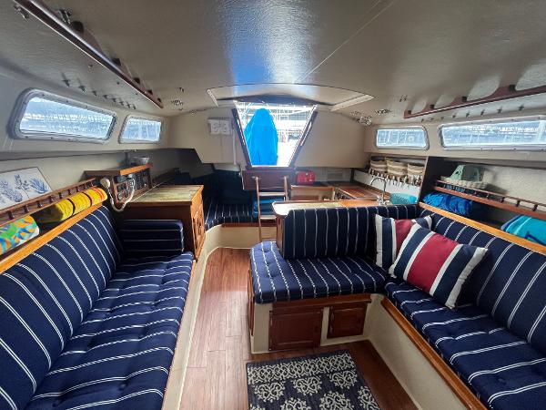 Interior of a 1980 Catalina 30 sailboat with striped seating and wooden accents.