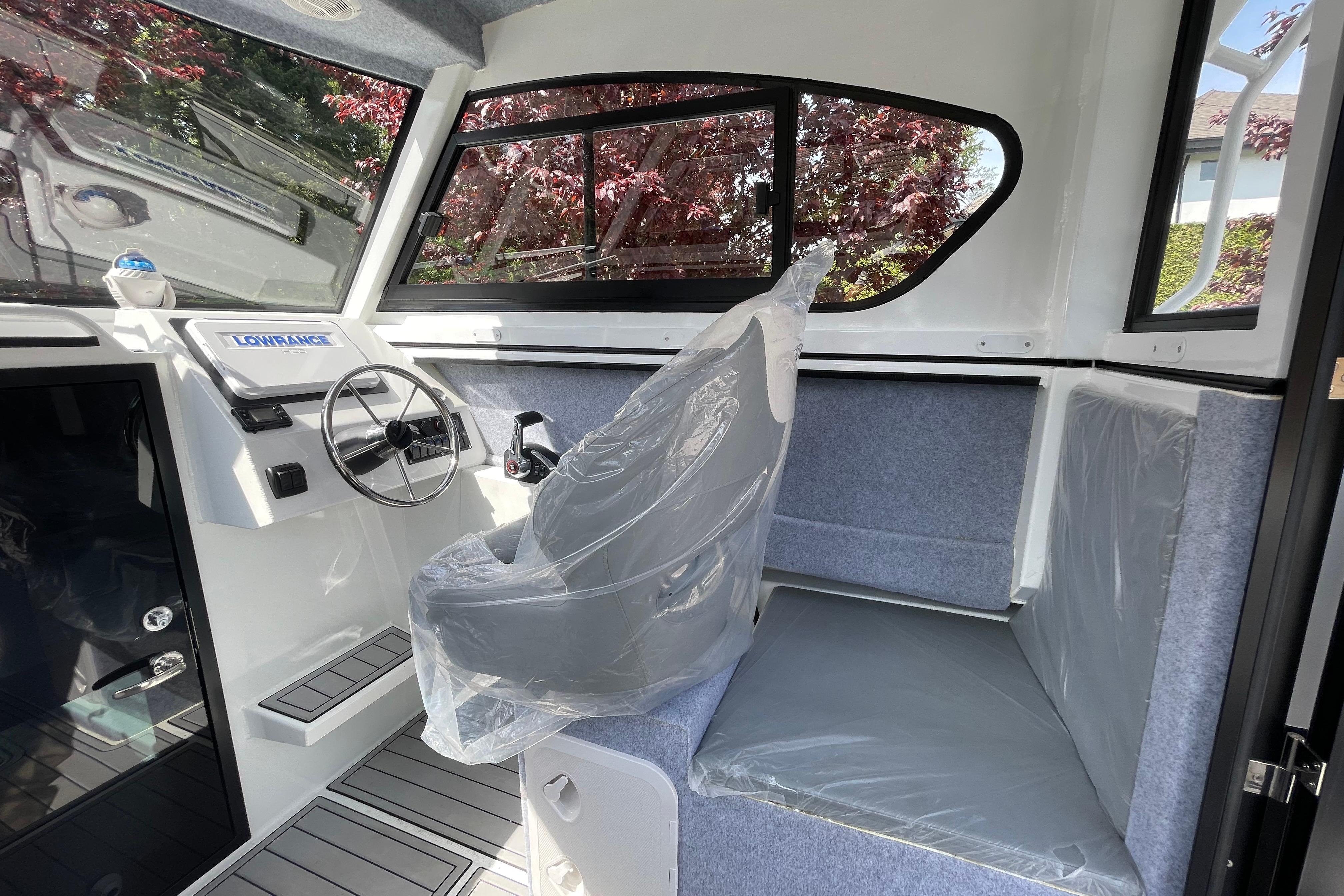 Interior of 2025 Custom Aluminum 7.5 Profisher boat with steering wheel and seating.