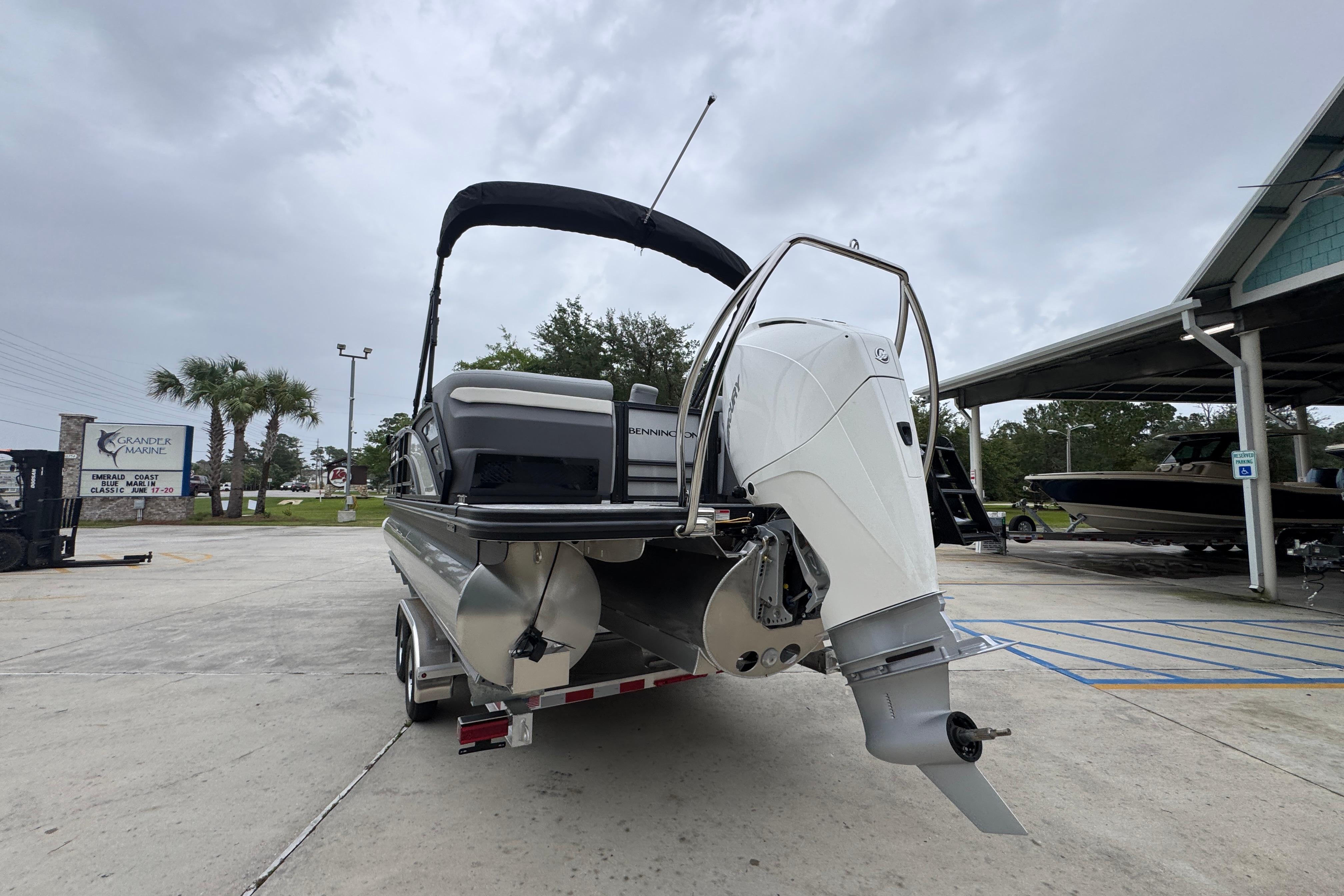 2027 Bennington 24 MFB pontoon boat with outboard motor, parked at a marina.