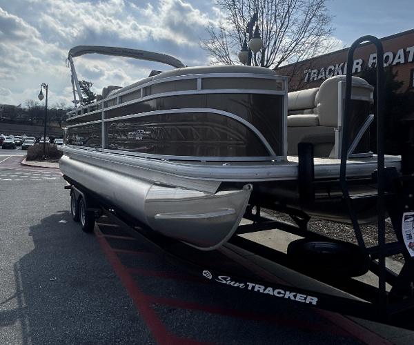 2025 Sun Tracker SportFish 22 DLX pontoon boat on trailer, parked outdoors.