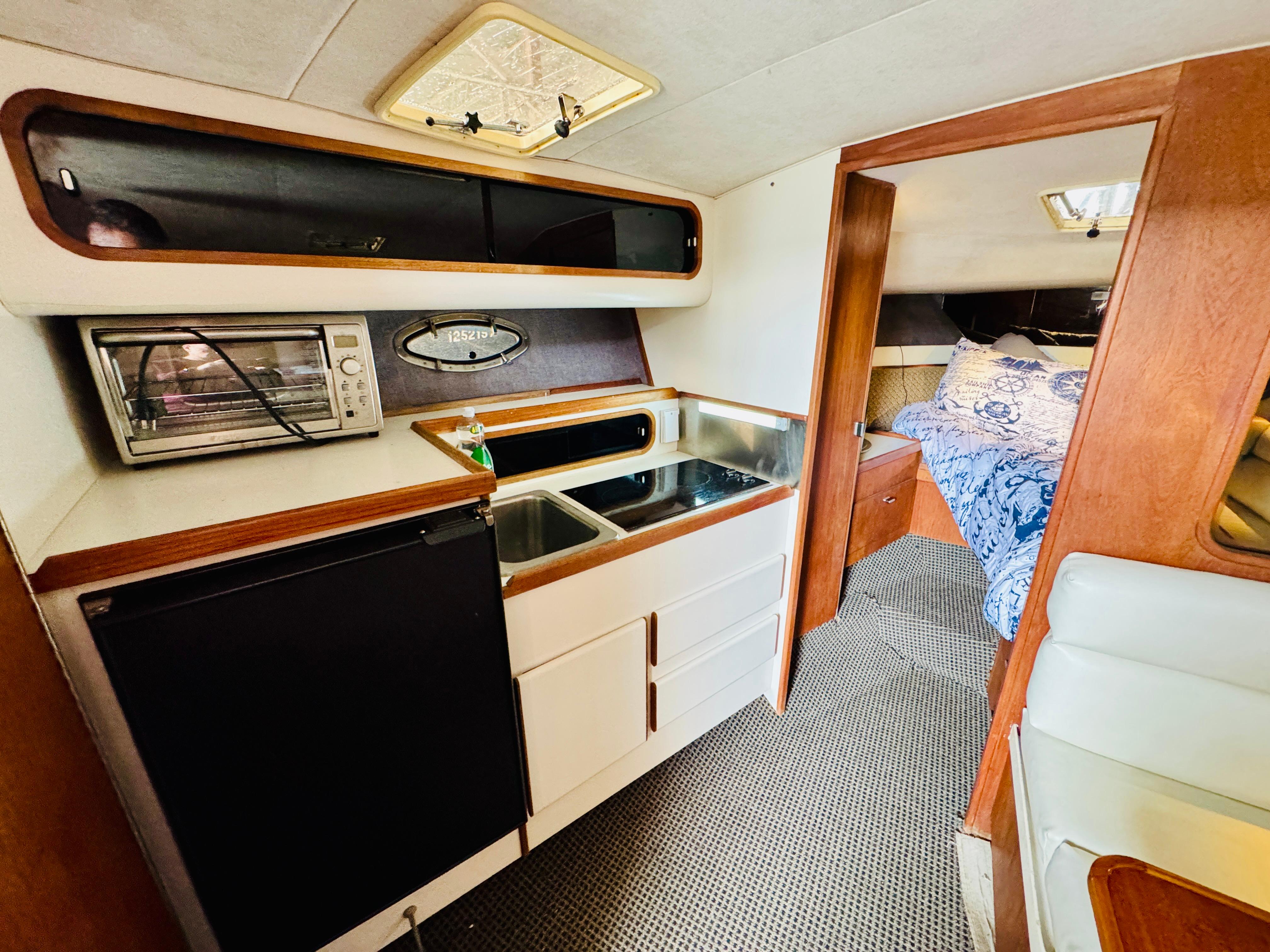 1988 Tiara Yachts 3100 Open interior with kitchenette and cozy sleeping area.
