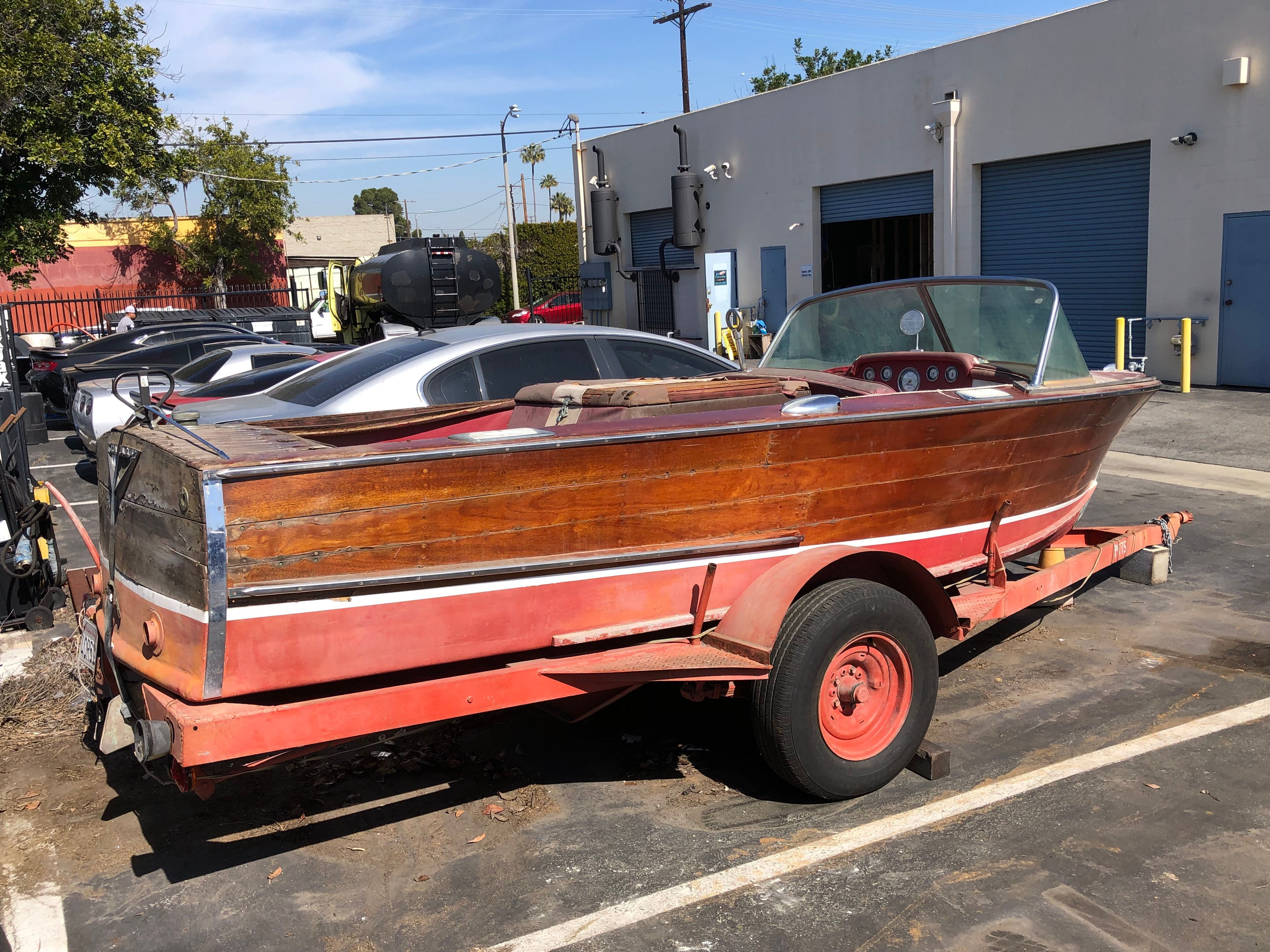A classic 1960 Century Resorter boat on a trailer in a parking lot.